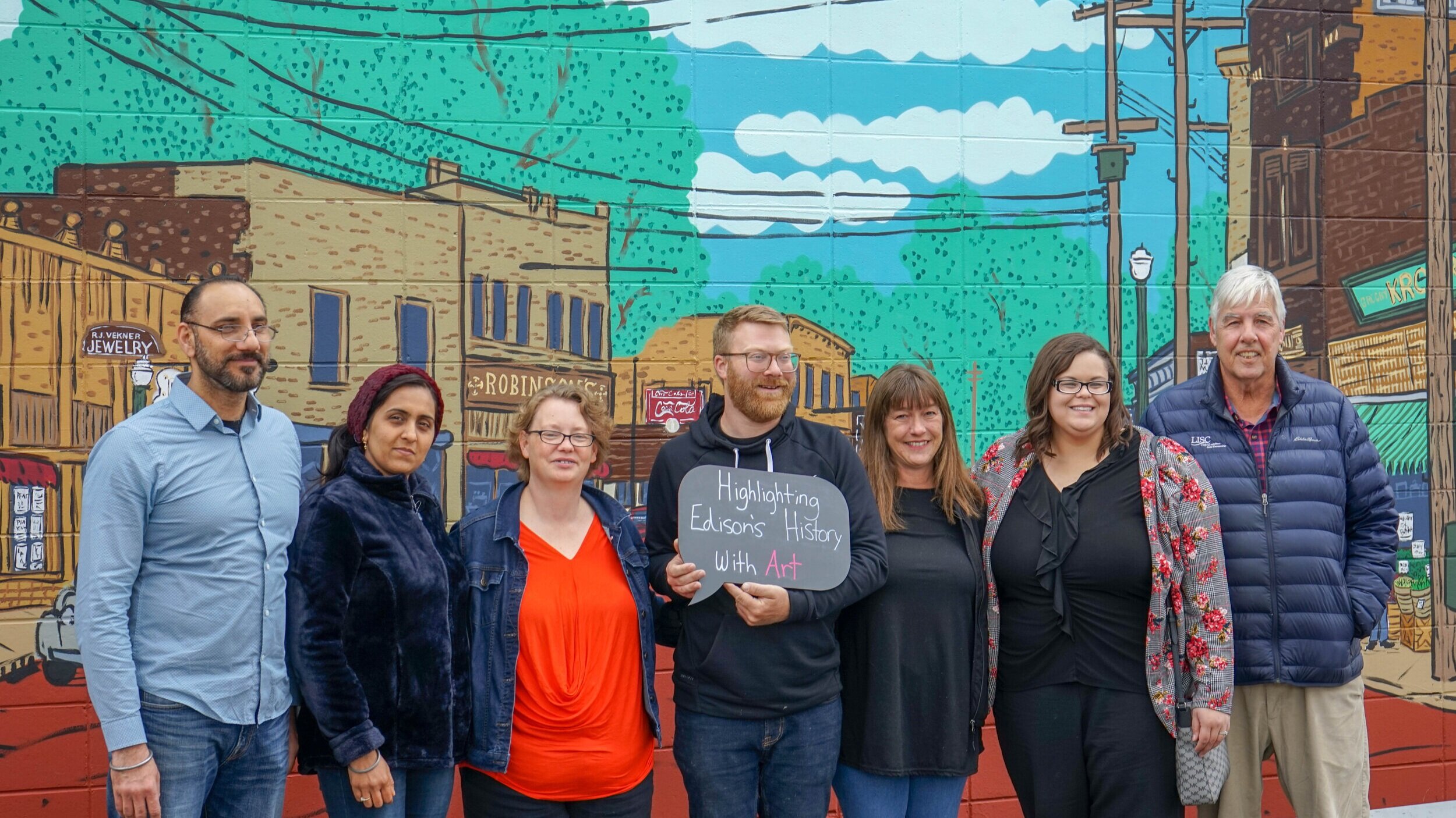  Standing in front of the new mural on the Howard’s Party Store building are the store’s owners, the mural artist, Patrick Hershberger, of Bonus Saves, ENA Director, Tammy Taylor, and LISC staff. 