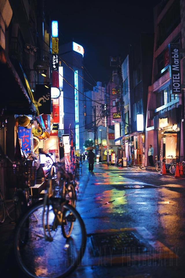 After a long day of wandering around Tokyo, I'd come back to the flat all knackered. Passed midnight, I put on my pjs ready to crash out when I realised it started to rain. And as we all know, rain makes for magical photos, so I thought as tired as I am, I'll just shoot a few outside the flat...what harm can it do? So I threw on my coat and went out. What started off as a few minutes...turned into a few hours. It was 2am when I realised I'd followed the neon lights all the way to the red light district in Shinjuku in my zebra onesie. Yes, I did look a bit dodgy. But I think this shot was worth it. P.s: Pictured isnt yet the red light district but rather a side street in Shinjuku along my journey. - Raquel Aly 