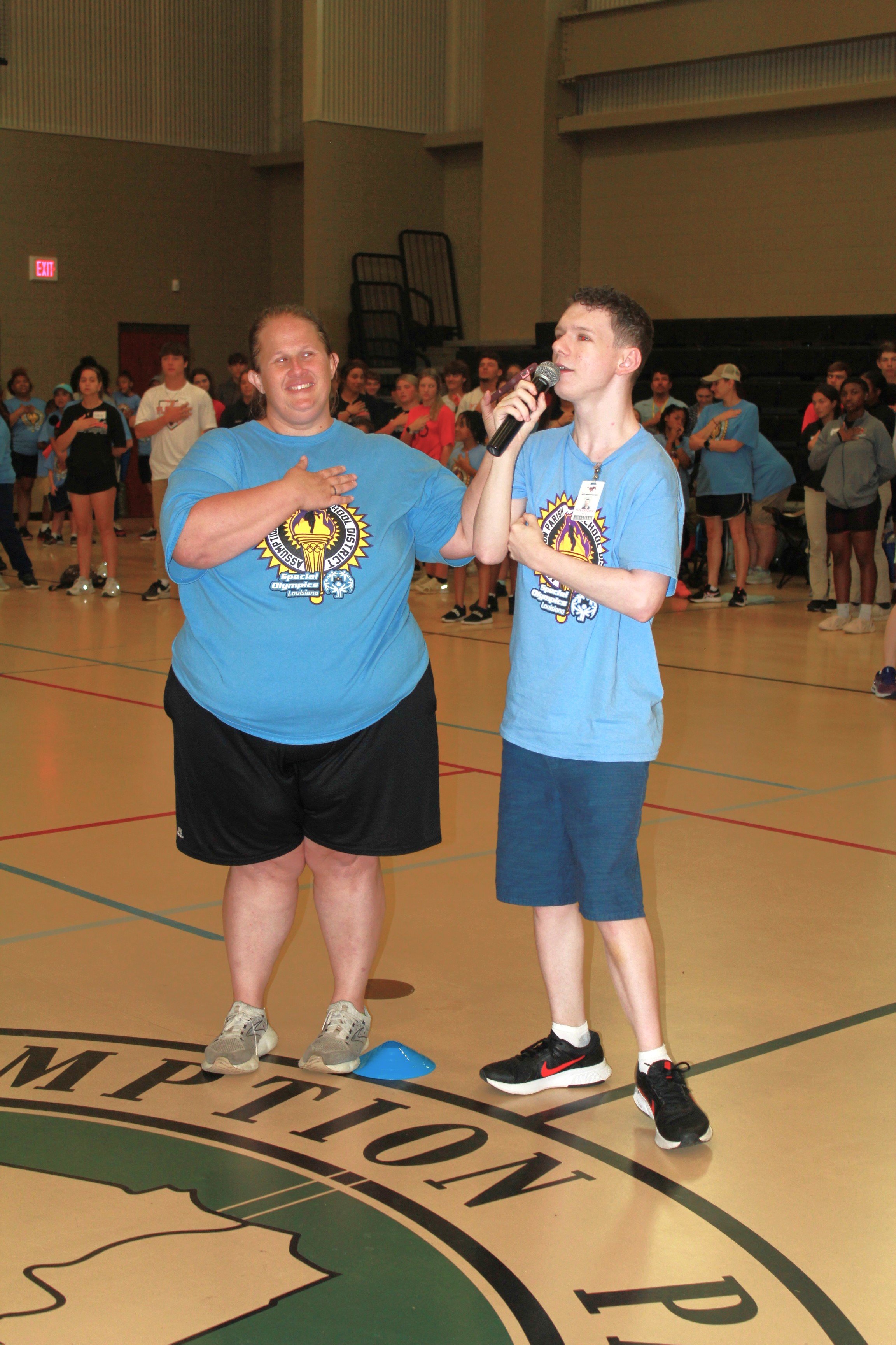  Assumption High School Senior Tate Cavalier, right, sang the National Anthem at the Assumption Parish Public Schools Special Olympics on May 10.&nbsp; Teacher Heather Templet, left, assisted him with the center-court presentation. 