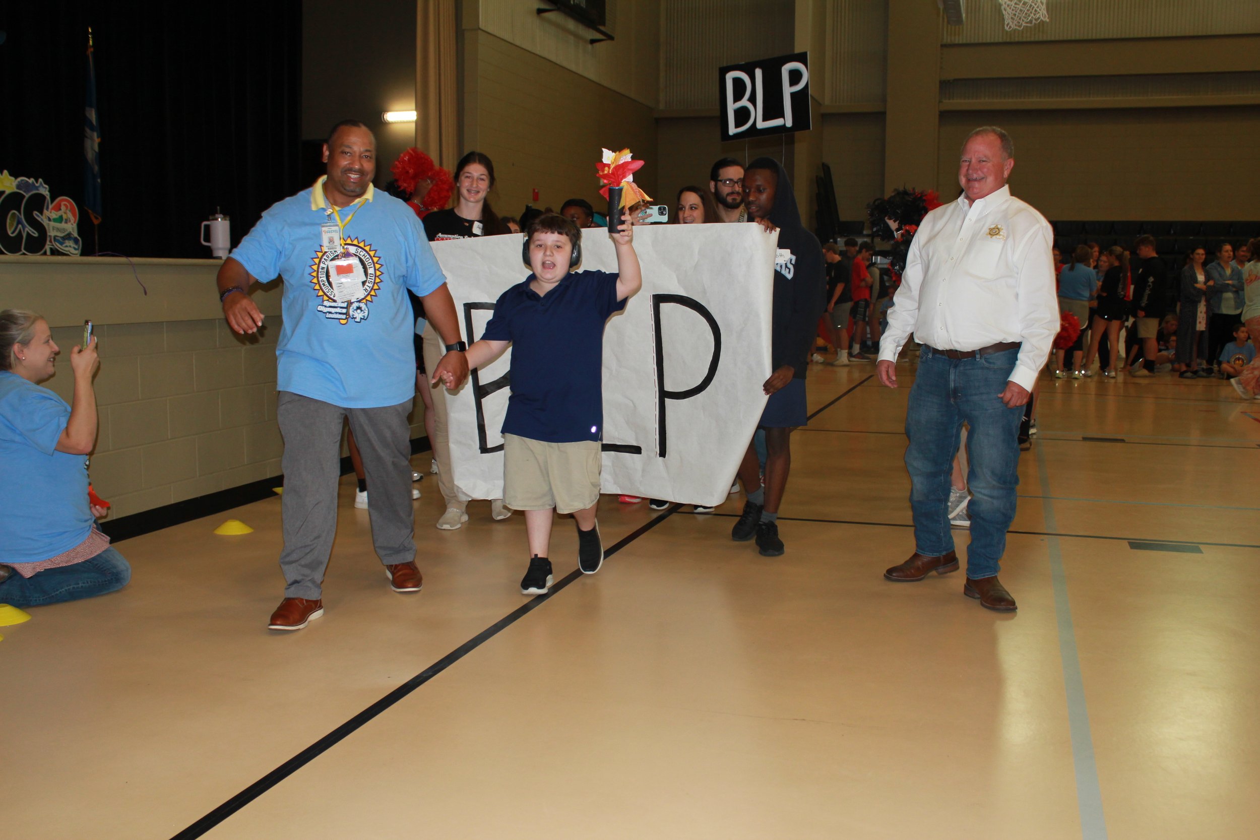  Superintendent Dr. John Barthelemy, left, student Tucker Barras, and Sheriff Leland Falcon lead the procession for Bayou L’Ourse Primary School during the start of the Assumption Parish Public School Special Olympics.&nbsp; The event was held May 10