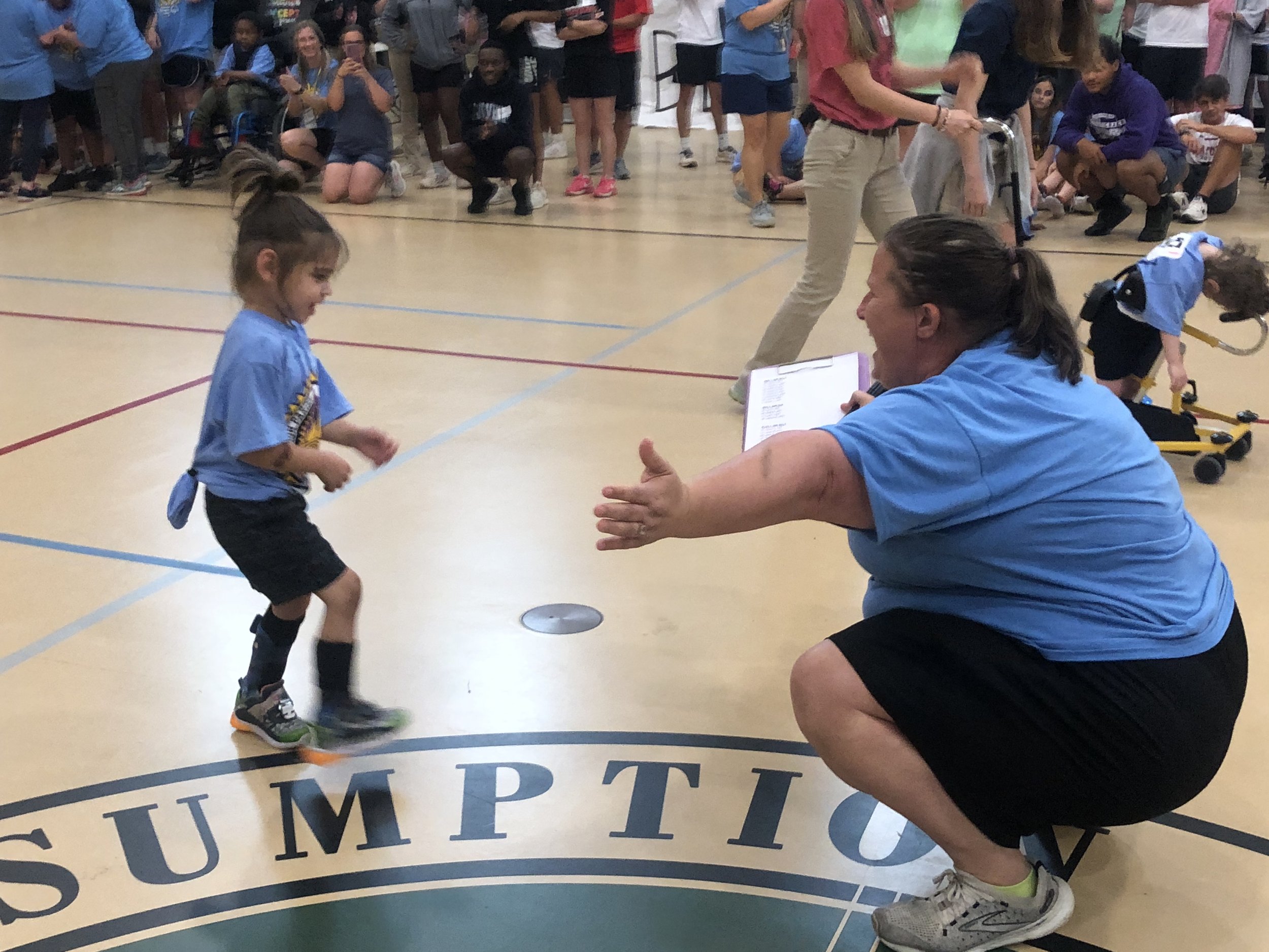  Assumption Parish Public Schools Special Olympic Athlete Killian Mabe races across the gym floor of the Assumption Parish Civic Center to be greeted by event coordinator and teacher Heather Templet. 