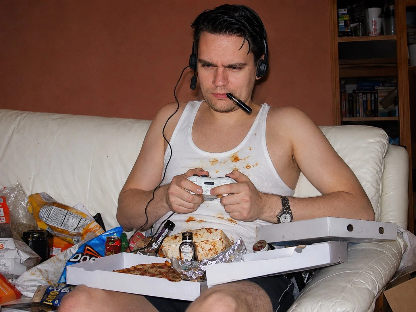 KI-erstelltes Meme zeigt Alexander Voigt beim Videospielen mit einer PIzzaschachtel und Müll auf dem Schoß. Satirische Fotomontage aus Das Letzte Wiki.