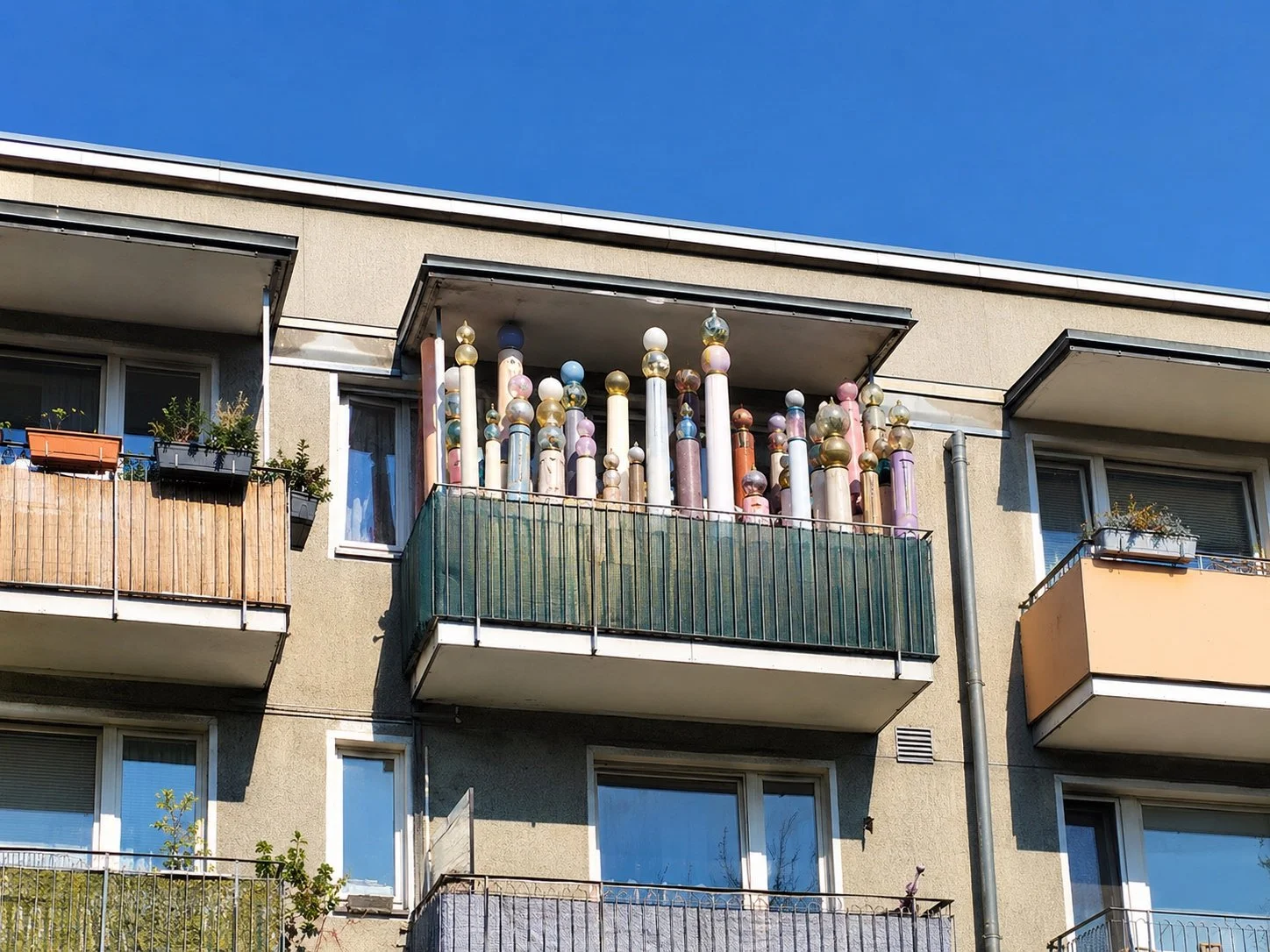 KI-generiertes Satirebild eines Wohnungskomplexes mit Balkon voller Akasha-Säulen. Parodie-Abbildung aus Das Letzte Wiki.