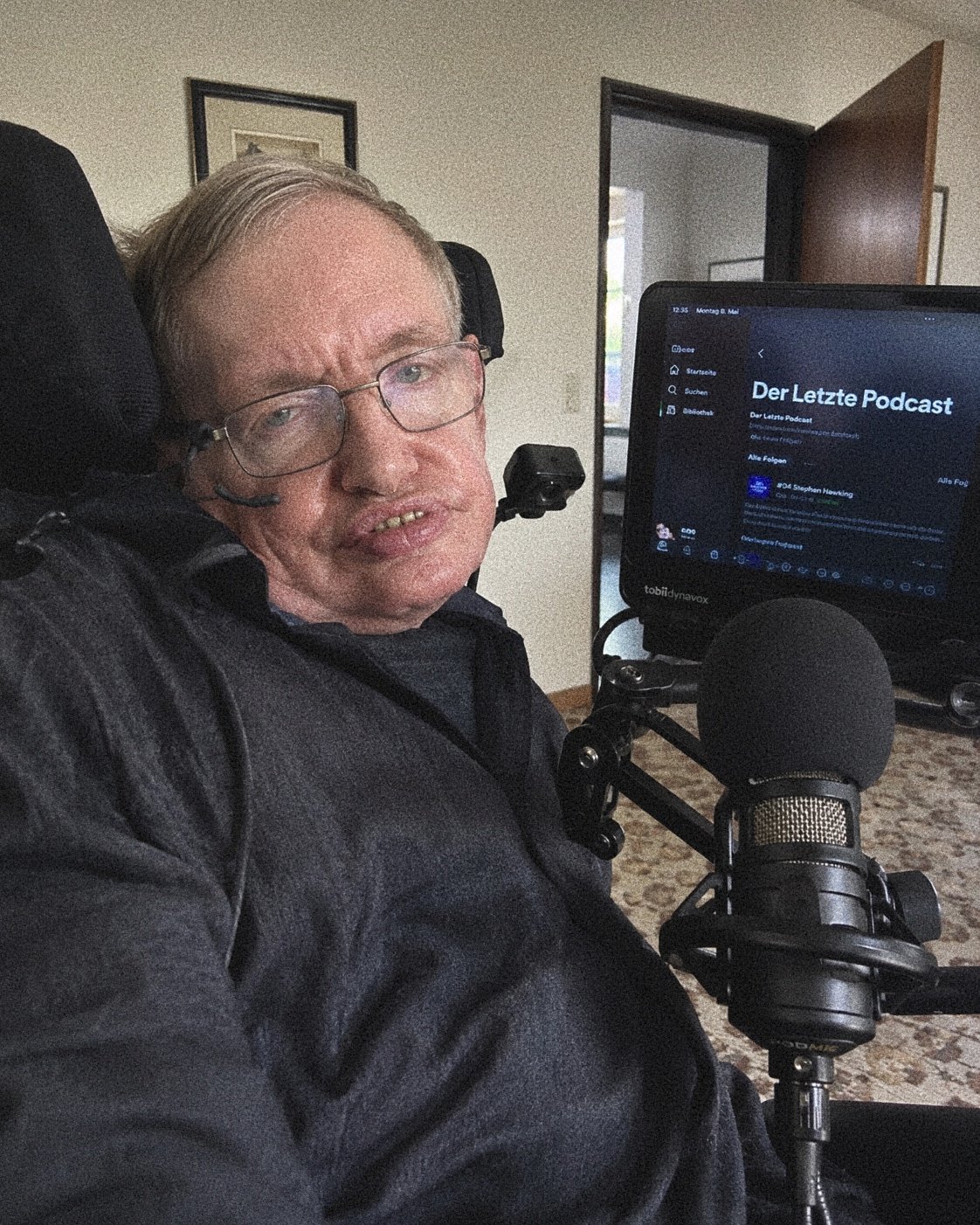 KI-generiertes Symbolbild des verstorbenen Physikers Stephen Hawking, der mit einem Aufnahmemikrofon vor seinem Bildschirm sitzt. Parodie des Satire-Lexikons Das Letzte Level.