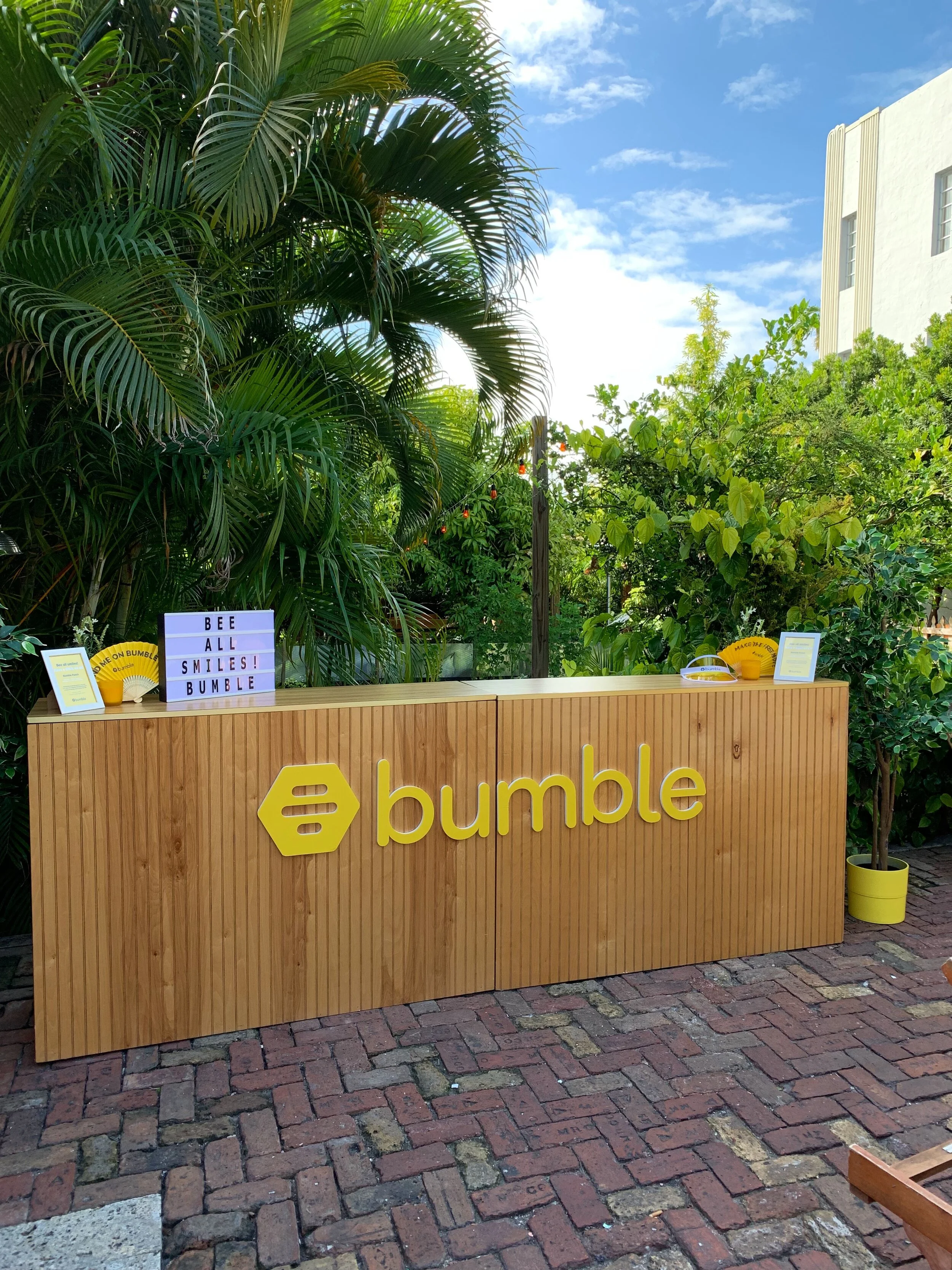 A wood paneled bar for rent with a logo on it for an event in Miami Beach