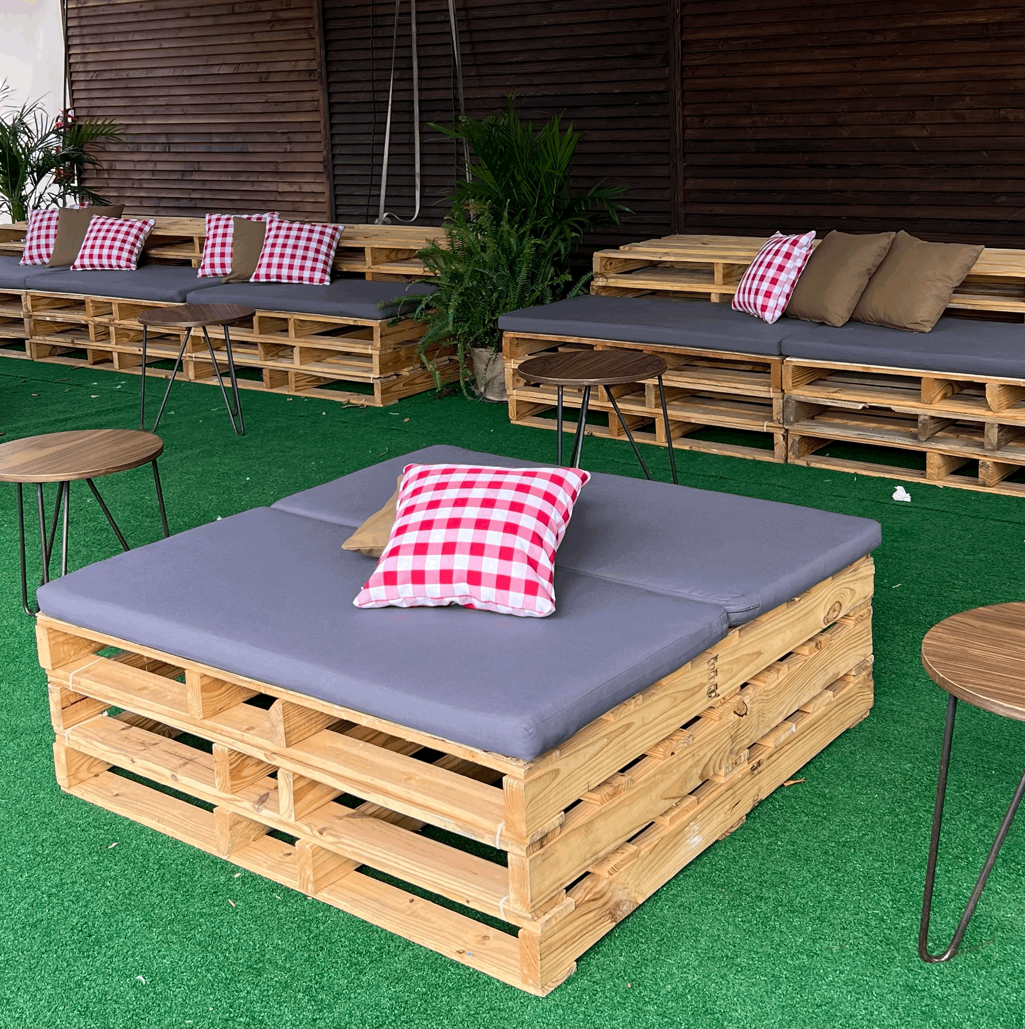 Red Gingham accent pillows as part of a seating lounge made out of wooden pallets for an event in Miami