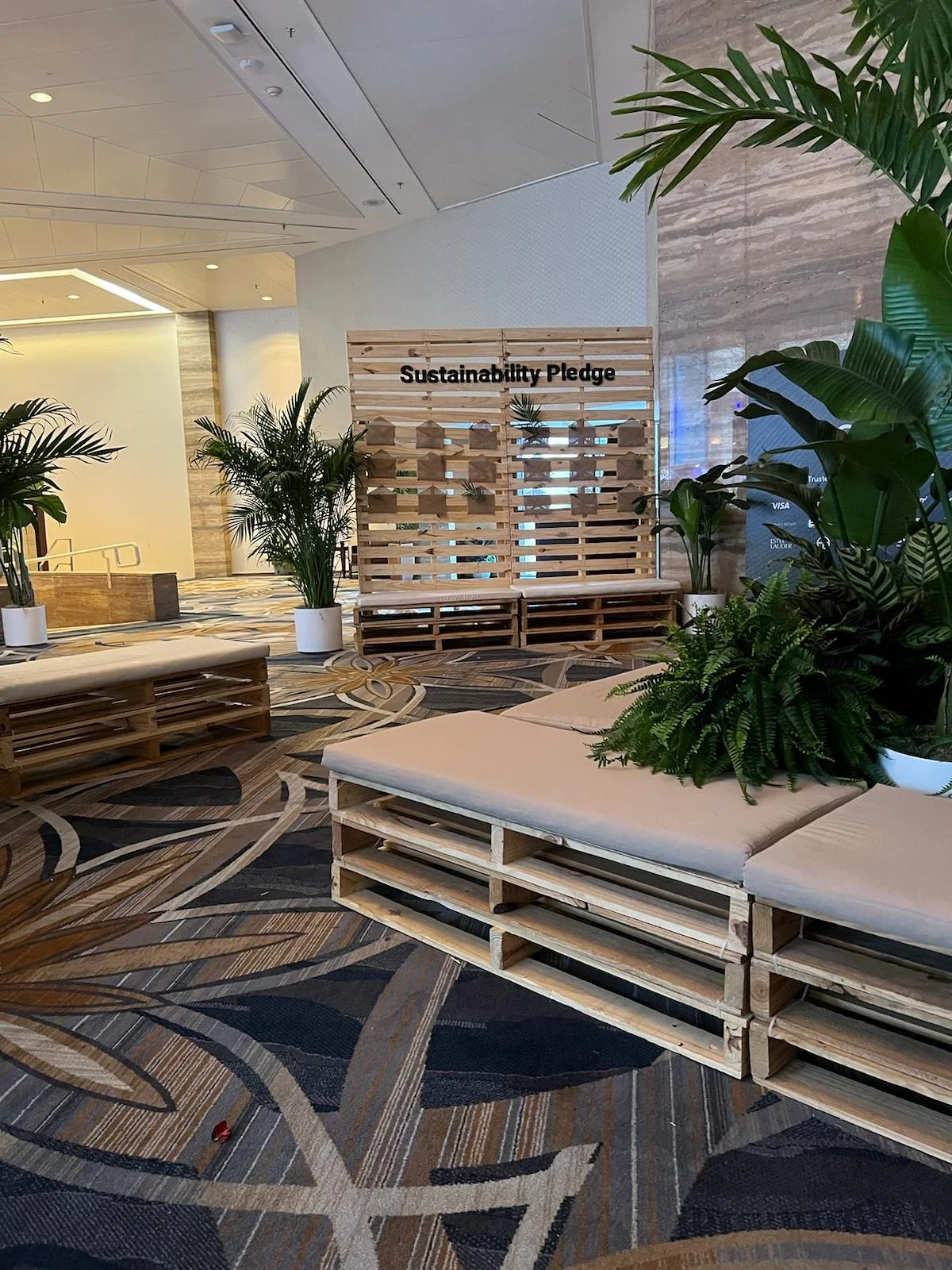 A sustainability lounge with pallet furniture as the main seating area and a pallet wall in the background with a custom sign and envelopes