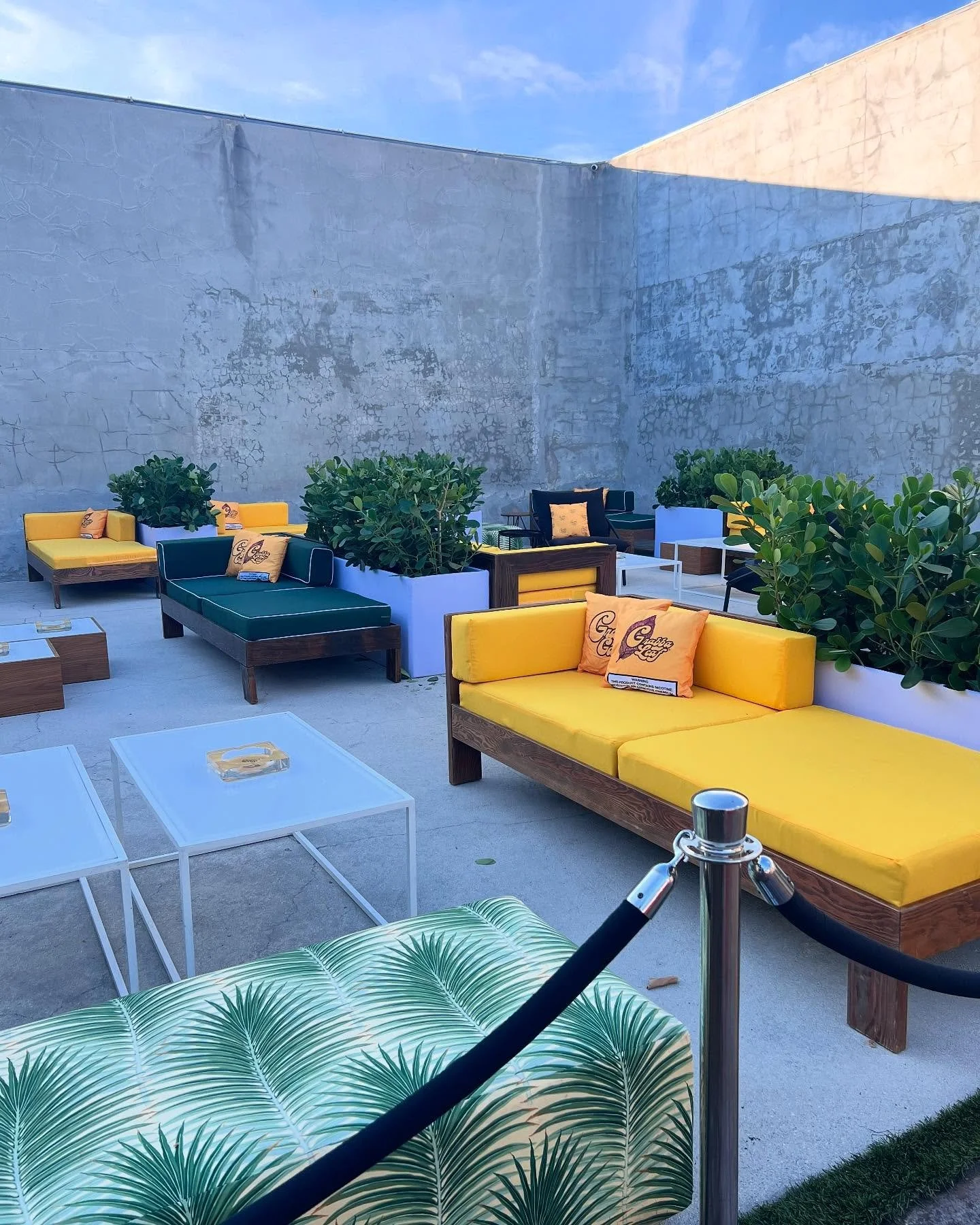 VIP lounge for @grabbaleaf at Maps Backlot in Wynwood. Our walnut frame lounge chairs with green and yellow cushions matched their brand colors perfectly, creating a tropical Miami vibe. Palm ottomans, greenery, custom accent pillows, and ashtrays co