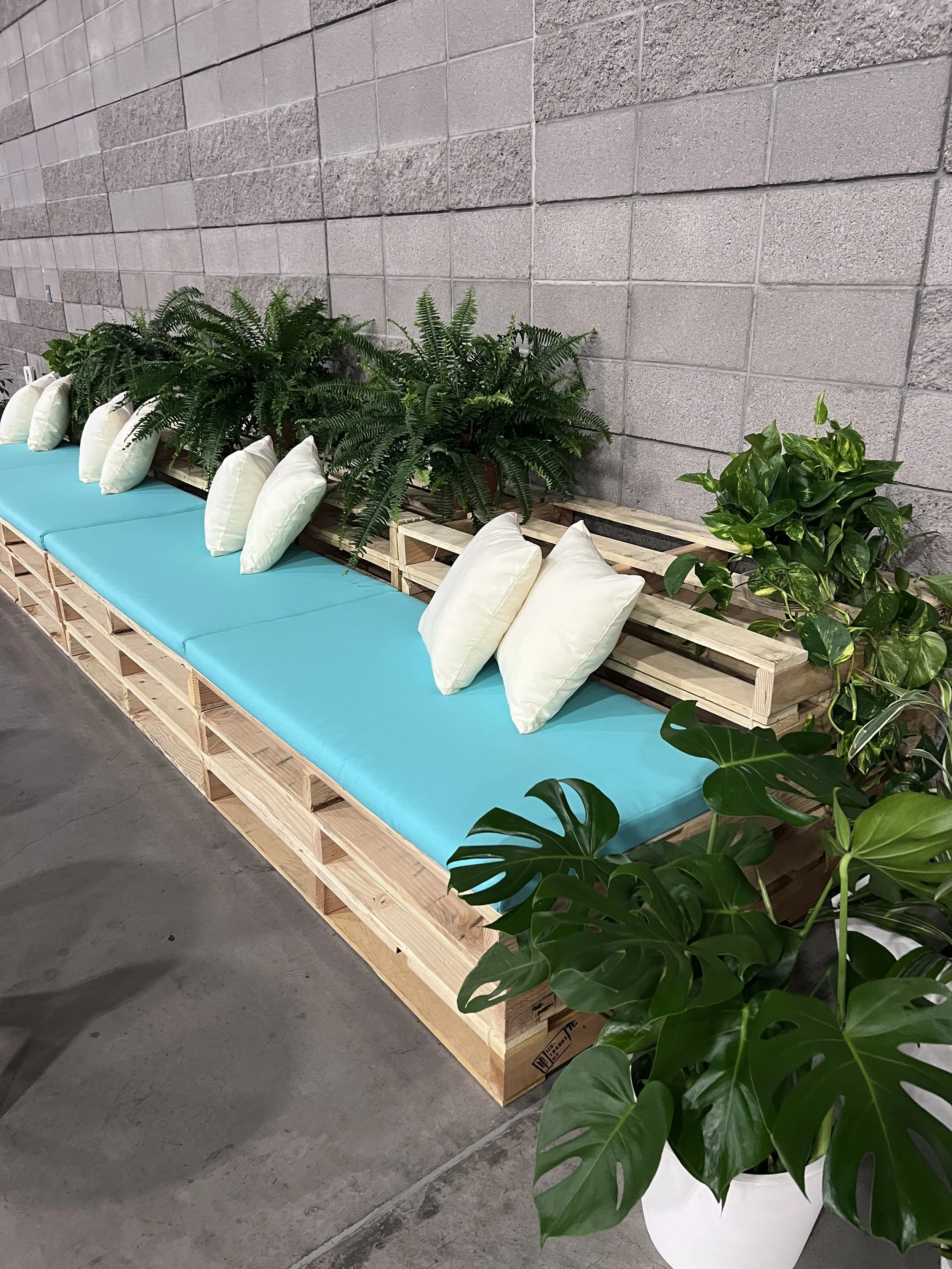 Sideline View Pallet furniture lounge in a conference in Las Vegas with Teal cushions and plants