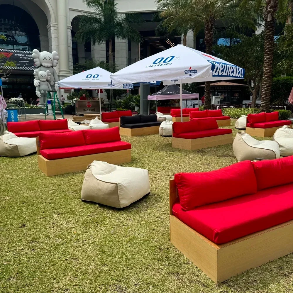 Sofas with red cushions facing a screen on a grass area in Miami