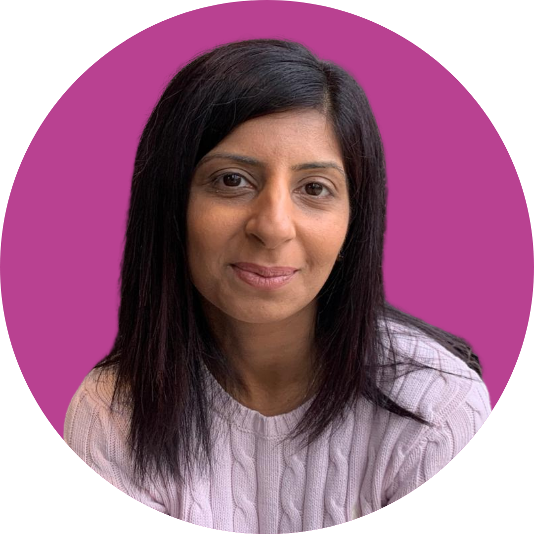 A woman with dark hair smiles at the camera. She is wearing a pale pink jumper and is set against a purple background.