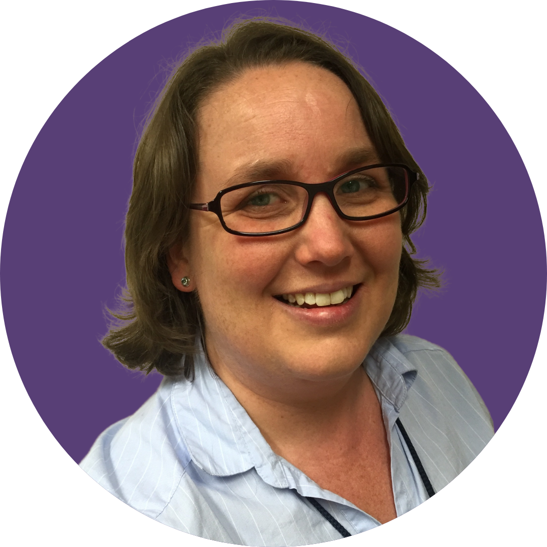 A woman with short hair smiles at the camera. She is wearing a blue shirt and set against a purple background.