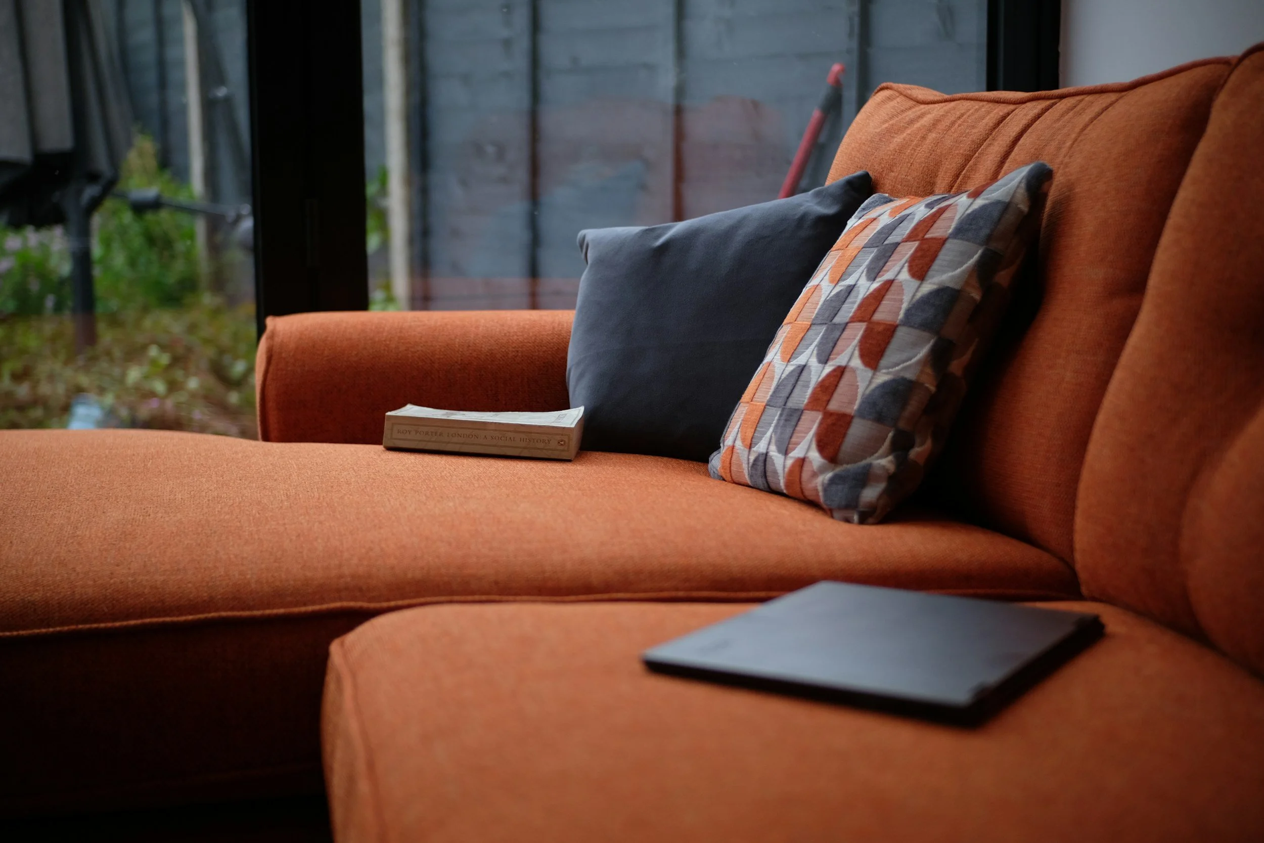 An orange sofa with cushions.