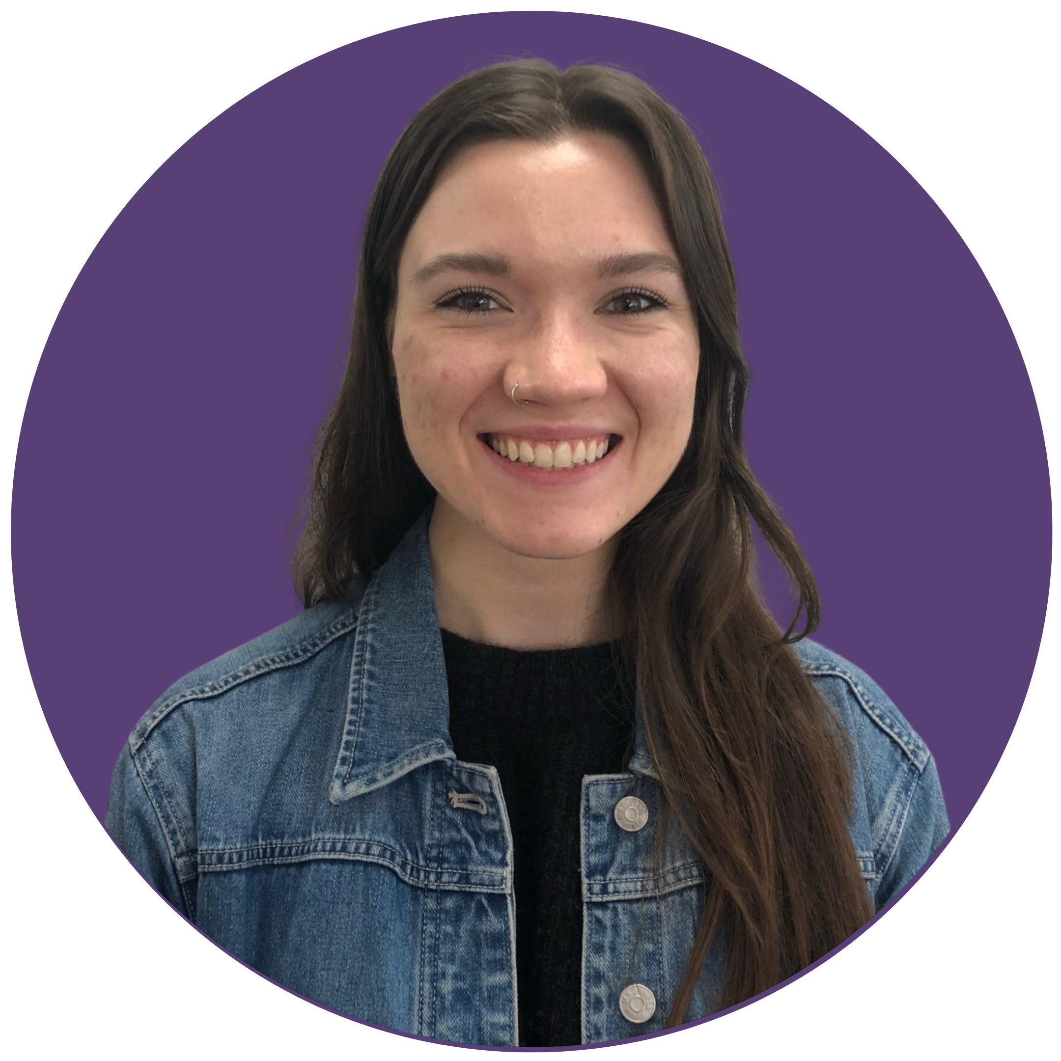 A woman with long dark hair smiles at the camera. She is wearing a denim jacket, and is set against a purple background.