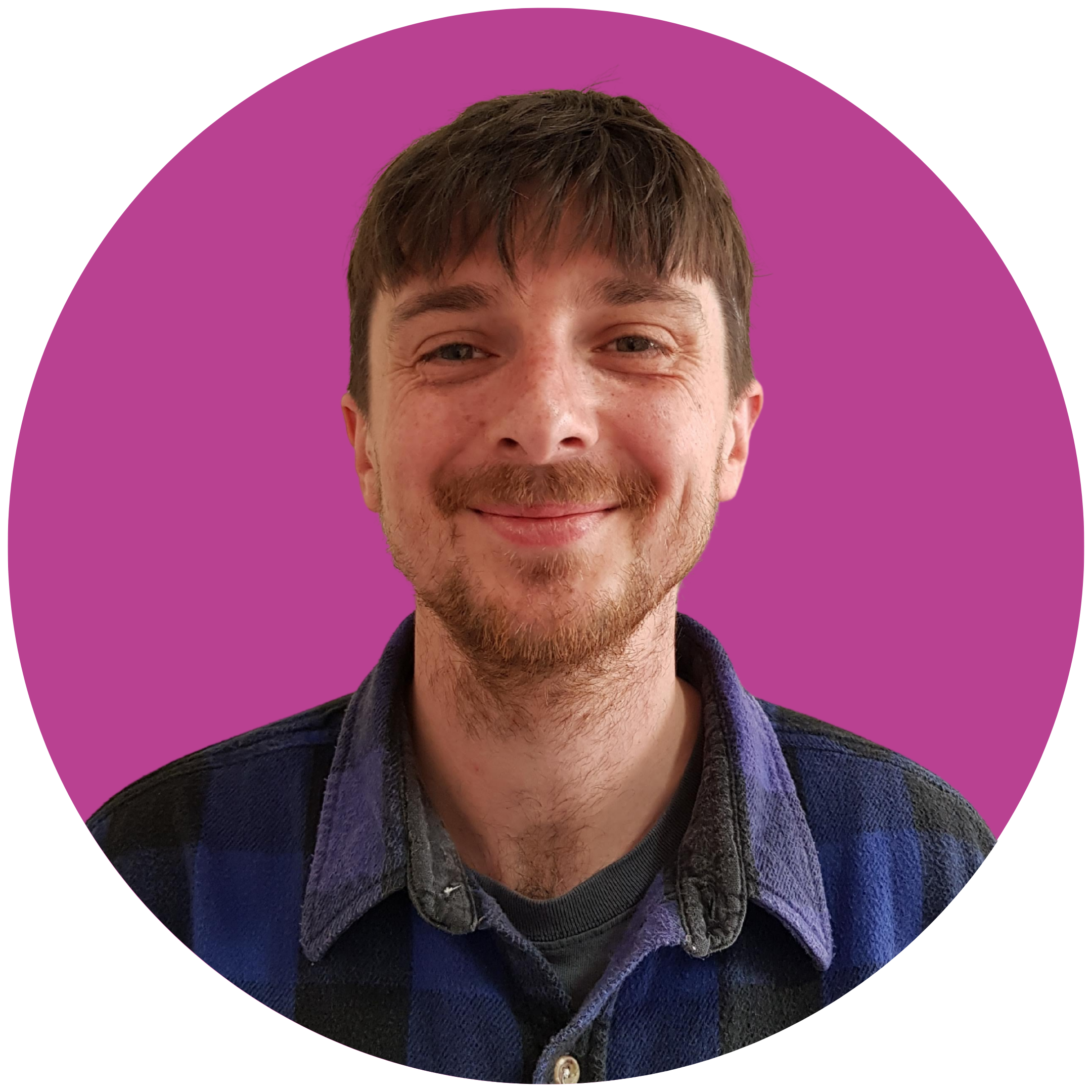 A man with a fringe and stubble smiles at the camera. He is wearing a blue shirt and is set against a purple background.