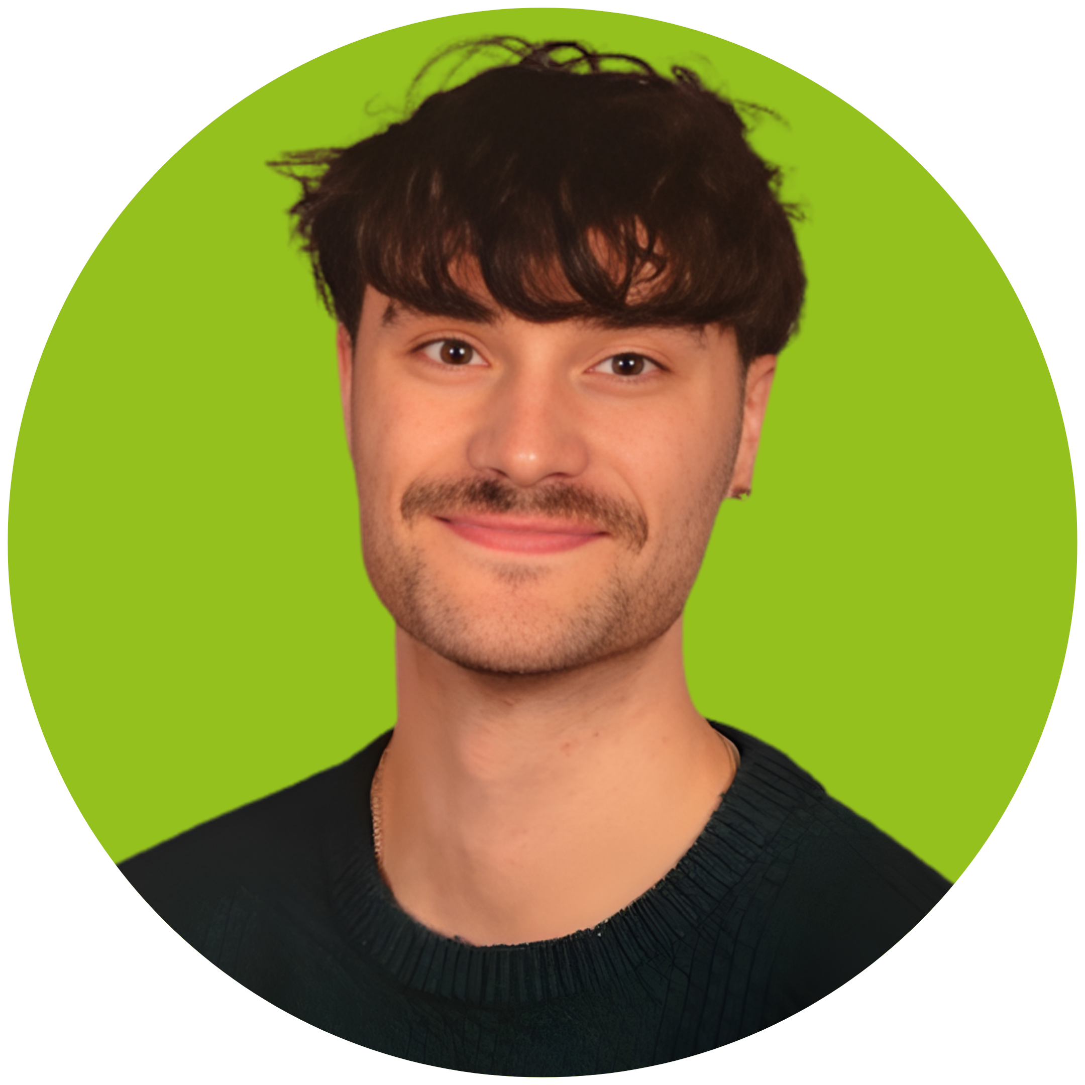 A man with dark brown hair smiles at the camera. He is wearing a black T Shirt and is set against a light green background.