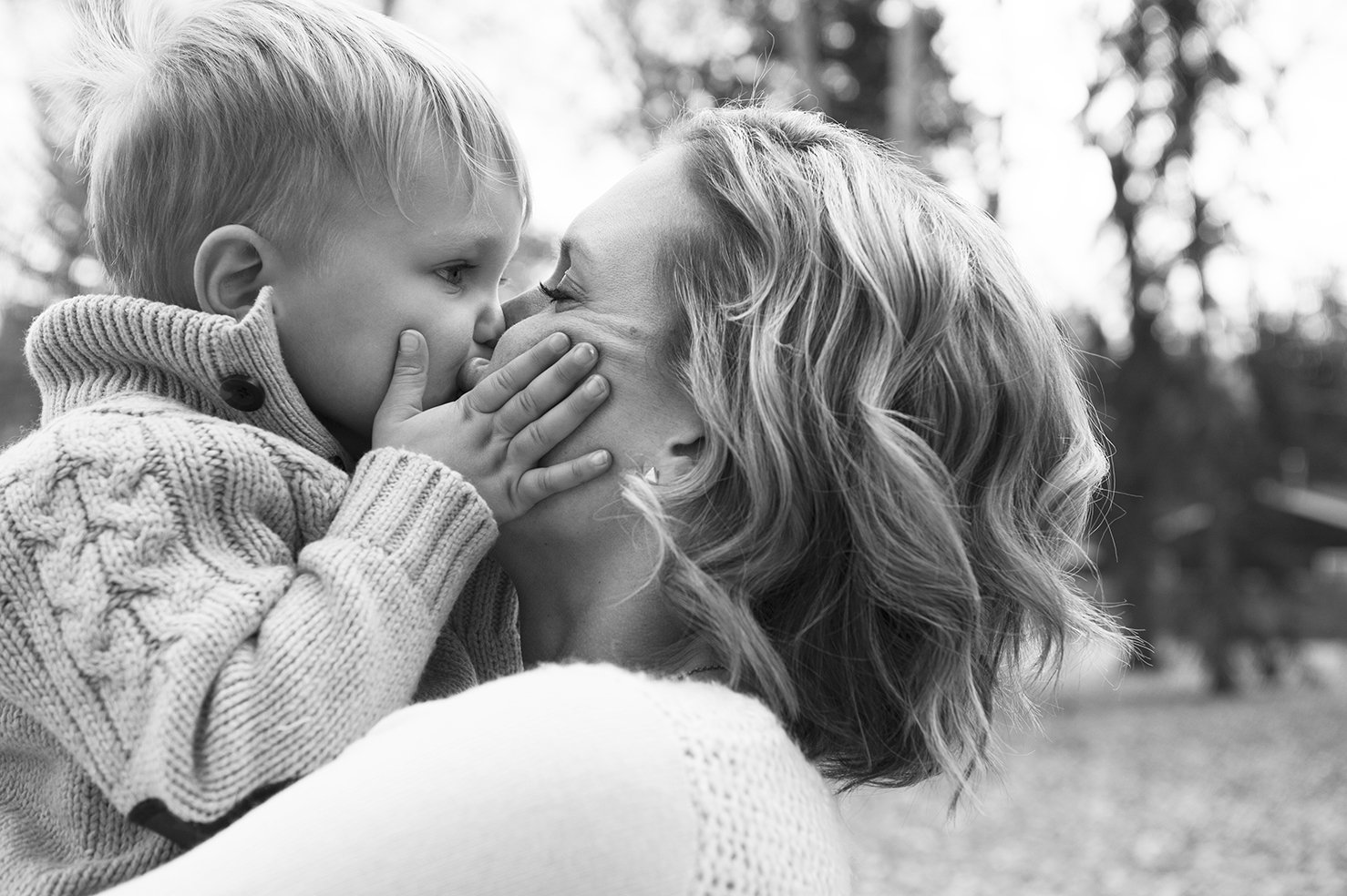 Black and white photo of young son giving his mom a kiss.jpg