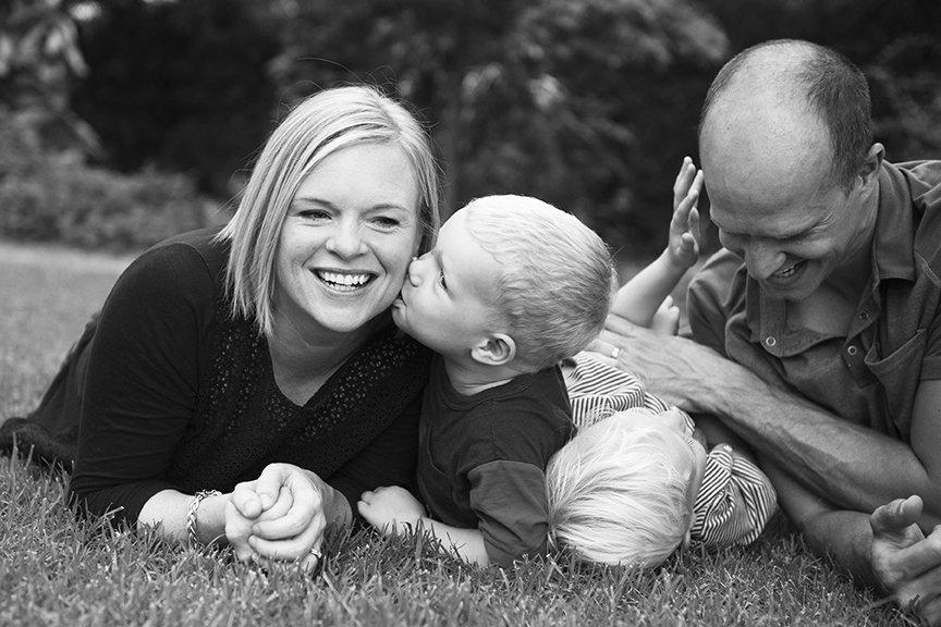 Black and white portrait of family laying in the grass palying.jpg