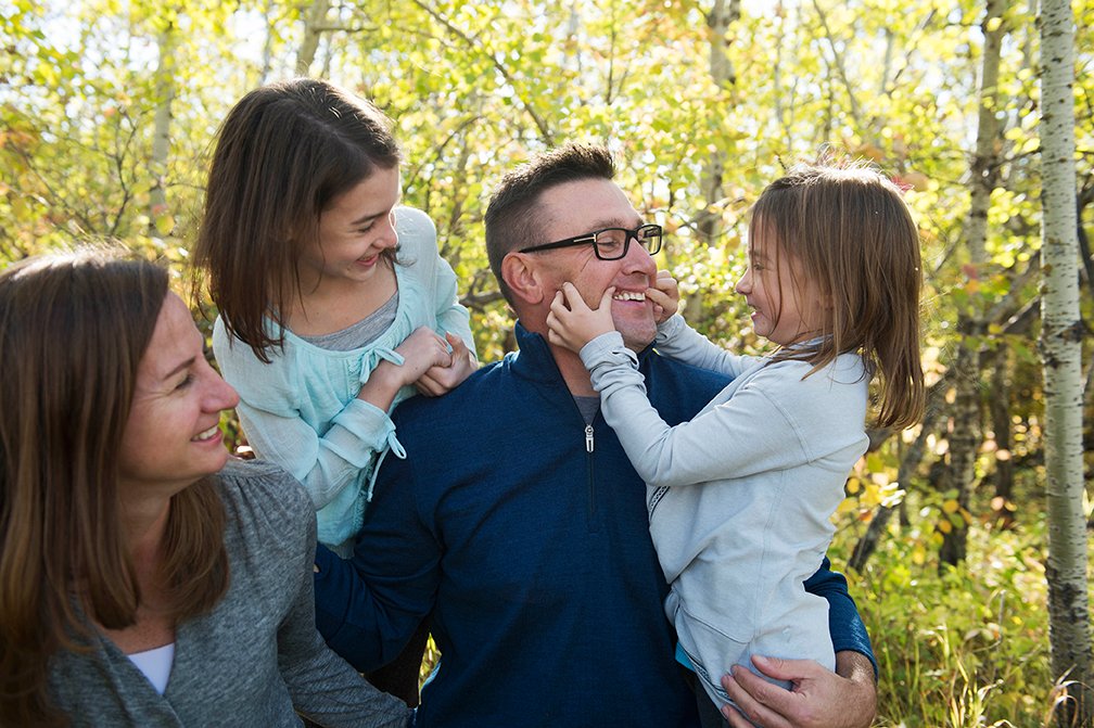 Candid family portrait with one daughter showing dad how to smile.jpg