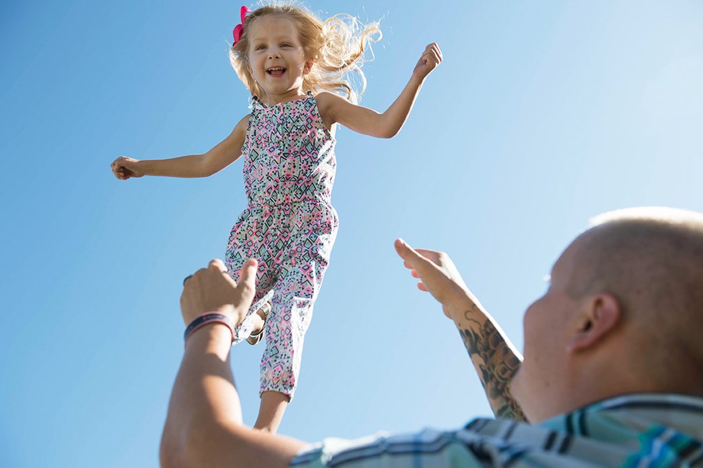 Dad throwing daughter in the air playfully.jpg