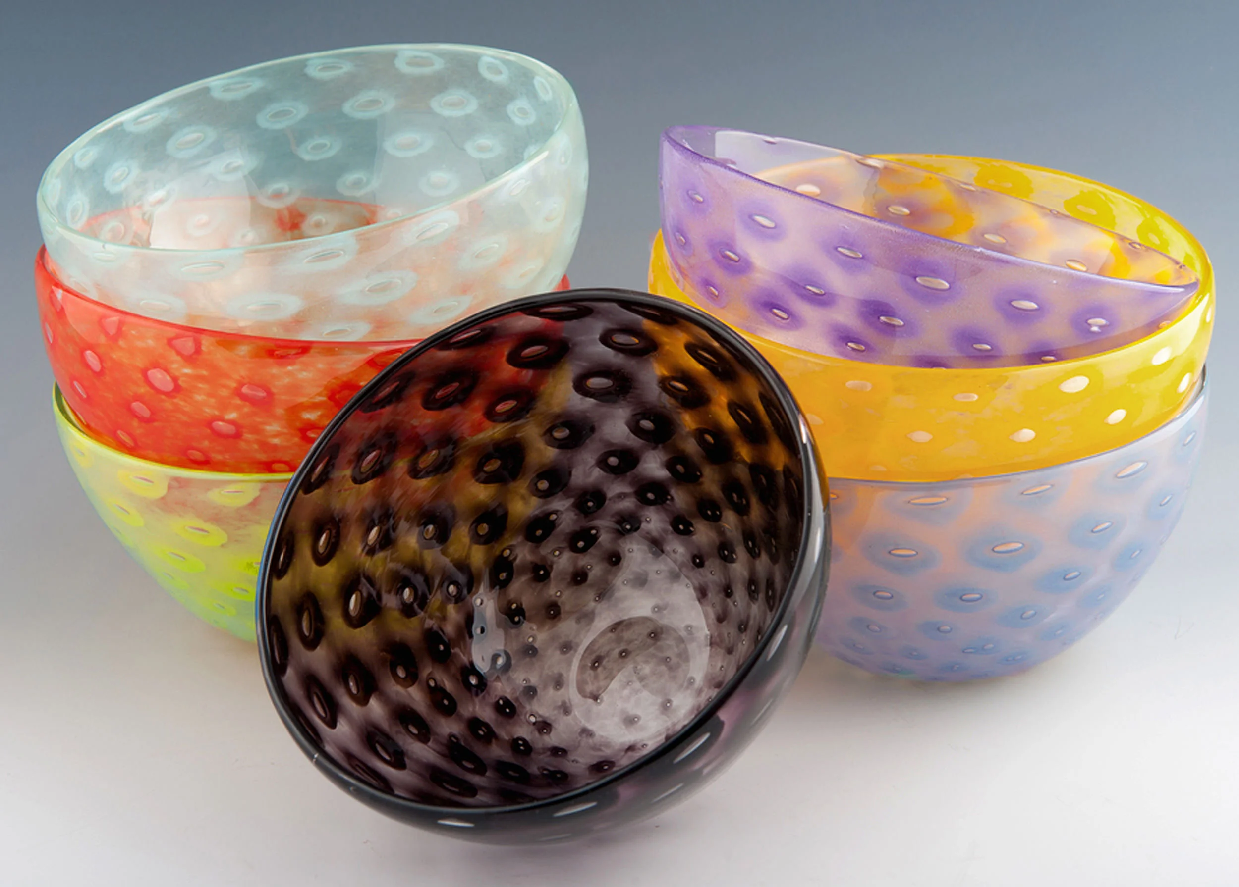 Bubble Bowl, seen here in Celadon, Vermillion, Lime (top to bottom, left stack). Black (middle), Violet, Yellow, Periwinkle (top to bottom, right stack). 
