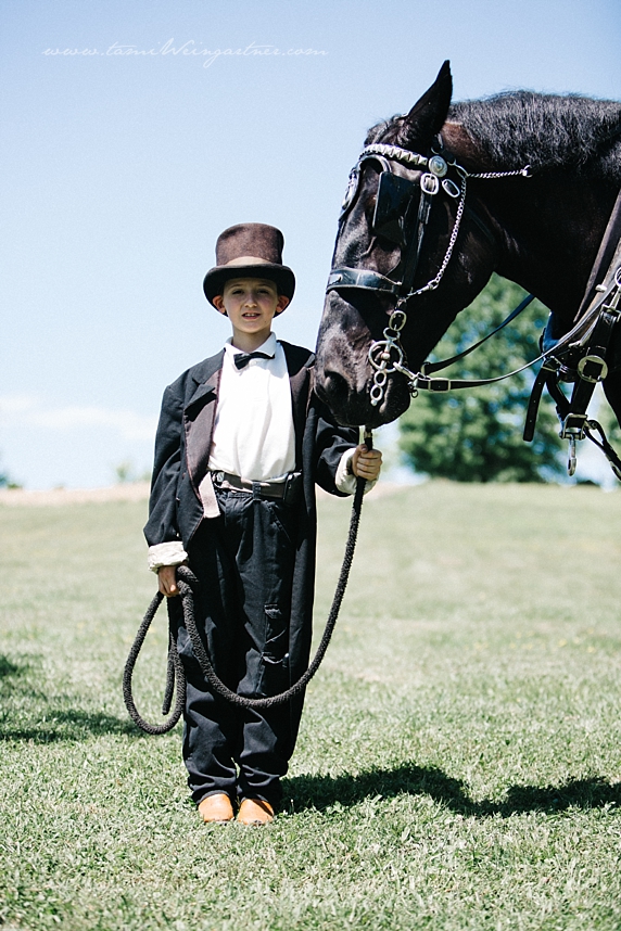 Young ring bearer holding a horse during a wedding ceremony