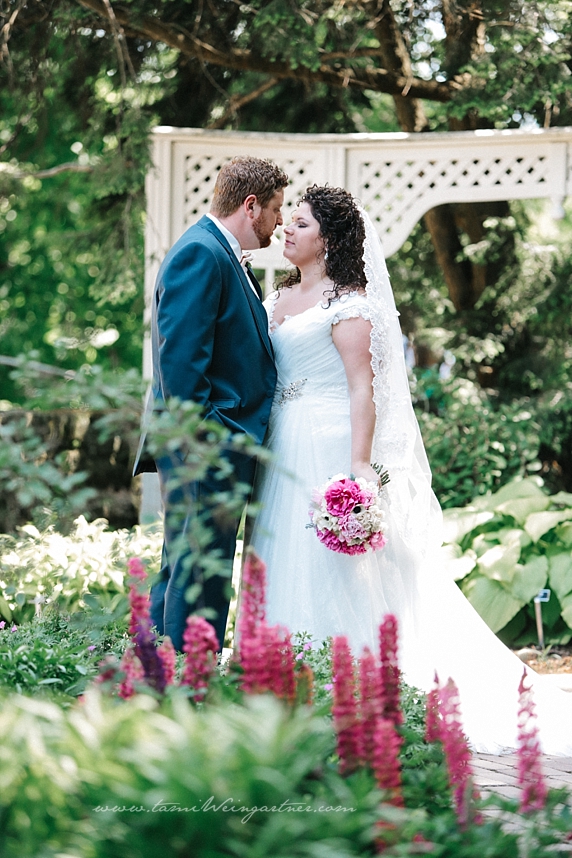 Gorgeous Bride and Groom pose in the flower garden at Fellowes Riverside Garden with purple flowers