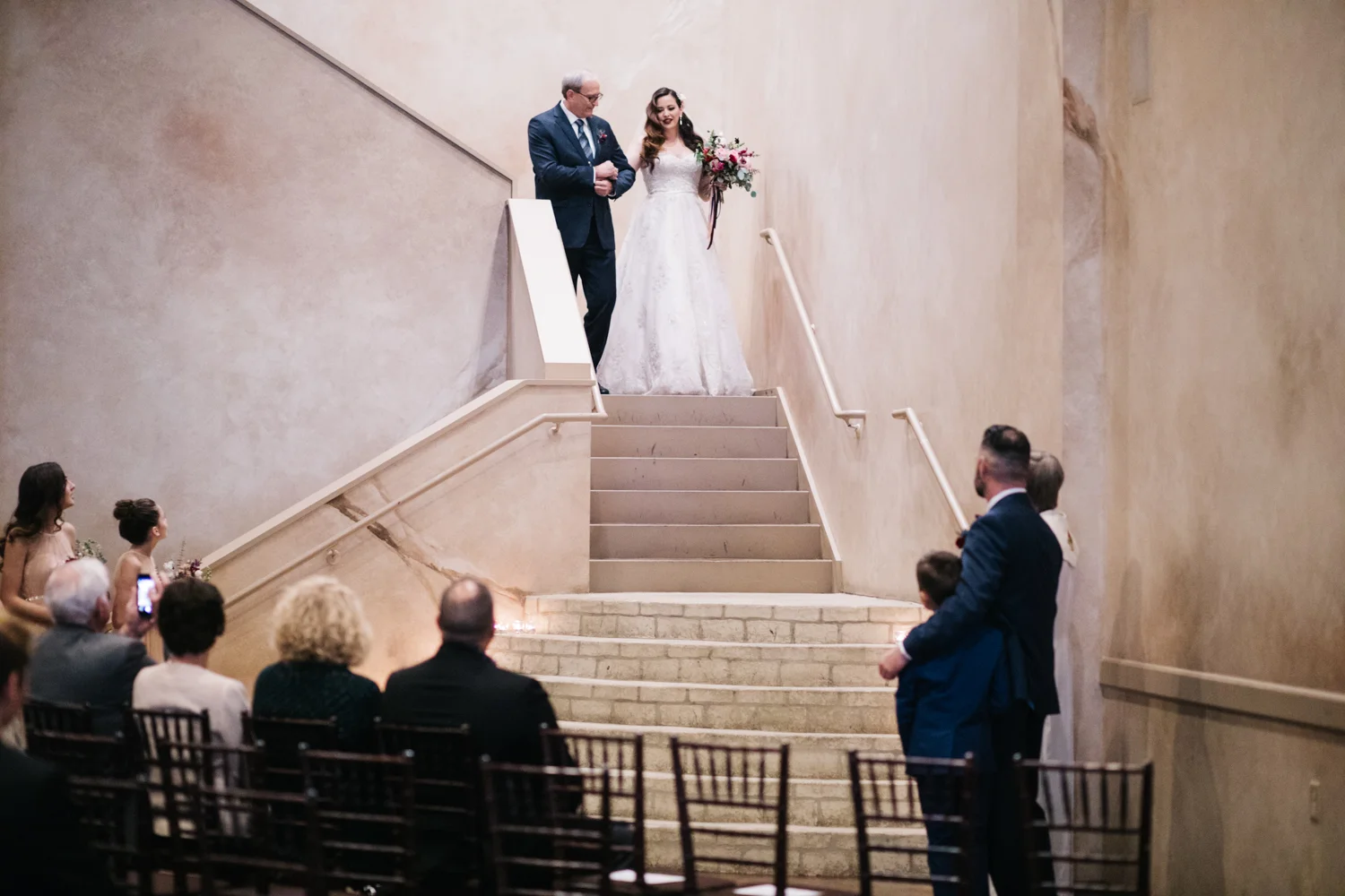 Bride coming down long staircase with her father.
