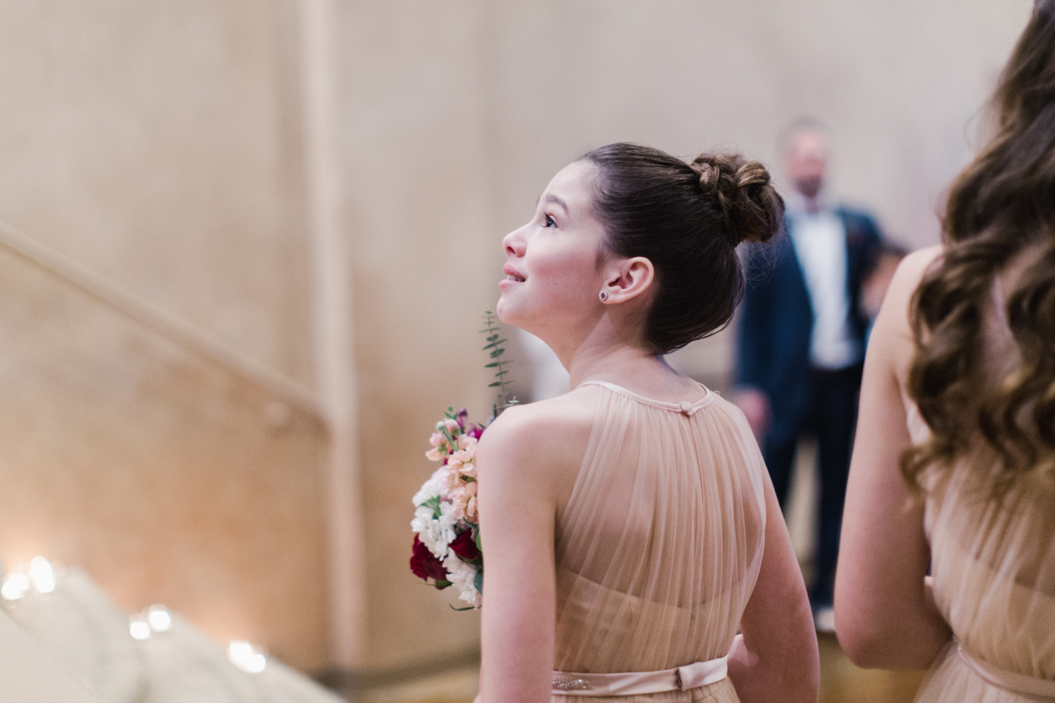 Bridesmaids watching her mother walk down the aisle with tears and emotion in her eyes.