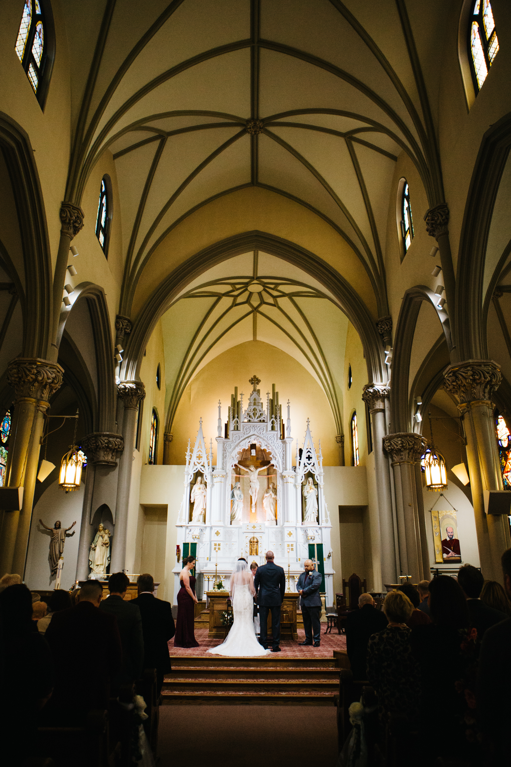 Wide angle view of the alter with a bride and groom standing in front during a wedding at St. Mary of The Mount on Grandview Ave in Pittsburgh PA.