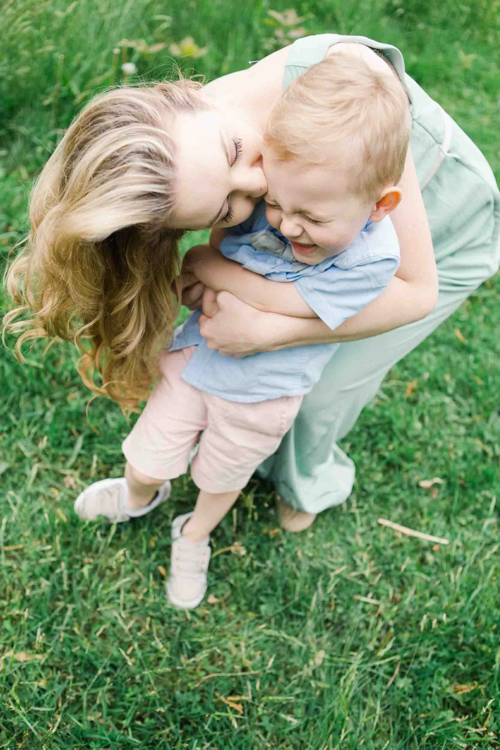 Mother and son in pastels share a sweet hug and kiss.