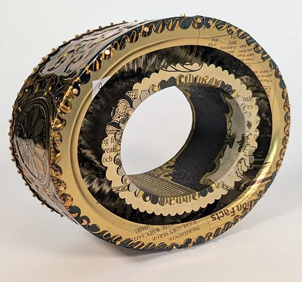24 Karat Corruptions is deep gold recycled tin cans that look beautiful but expose the ugly truth about the trump administration.