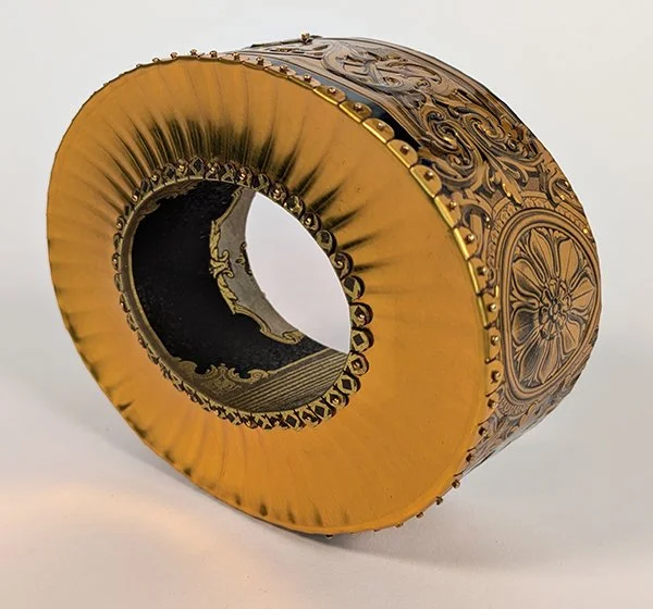 24 Karat Corruption is a bracelet made from Metallic gold to create an embossed texture to mimic the rug in the oval office.