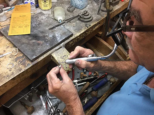 One of our jewelers polishes a custom-made gent's wedding band. Work with our staff to ensure that your jewelry is manufactured to your liking.