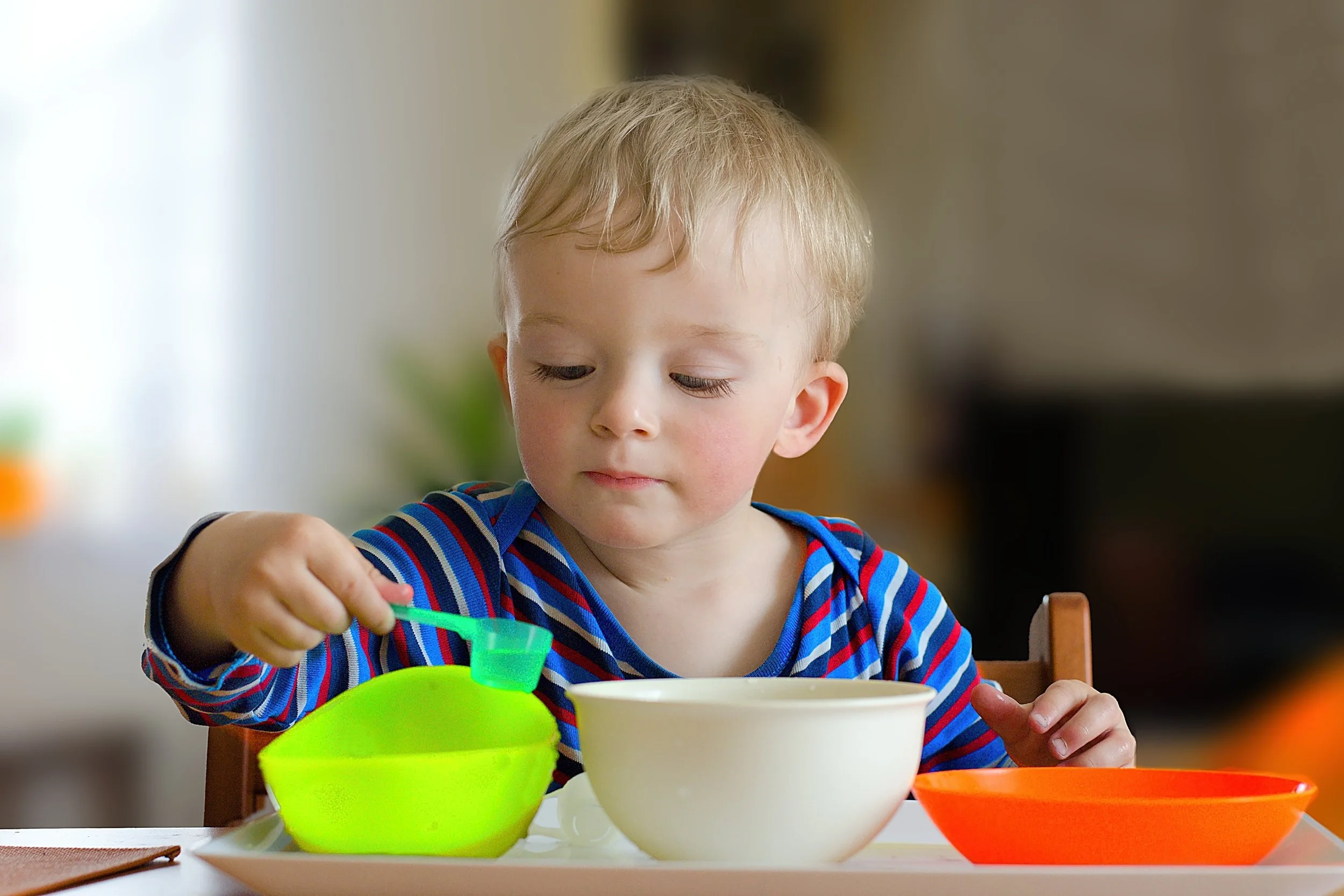 Toddler exploring with bowls and a spoon during a hands-on learning activity