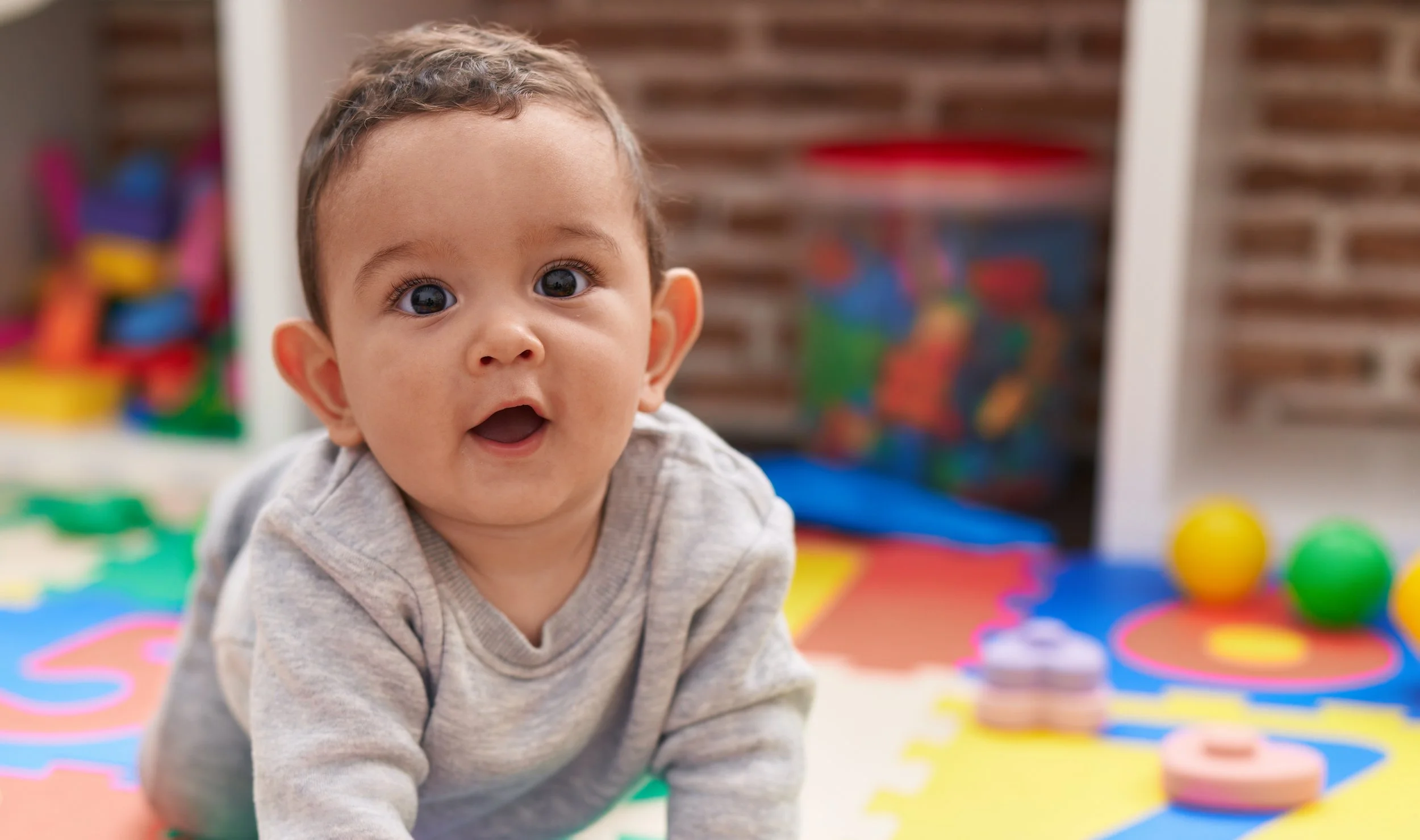 Infant enjoying tummy time in a colorful early learning classroom