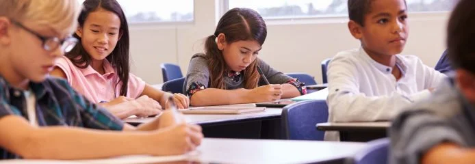 elementary-school-kids-working-at-their-desks-in-P9SAVC4-694x240.jpg