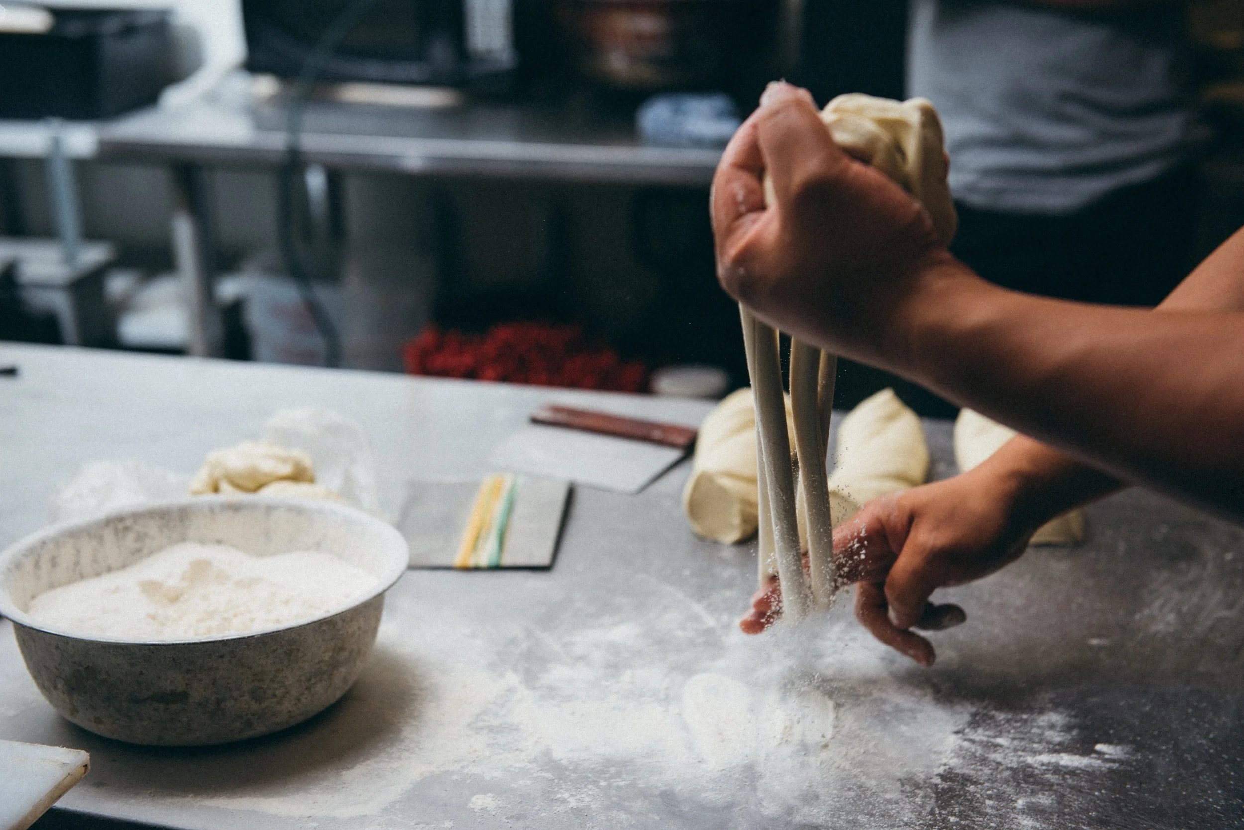12. Jacob's strokes are precise and betray years of practice perfecting the art. The speed of this process becomes evident, even in a photograph as the flour explodes off of the dough.