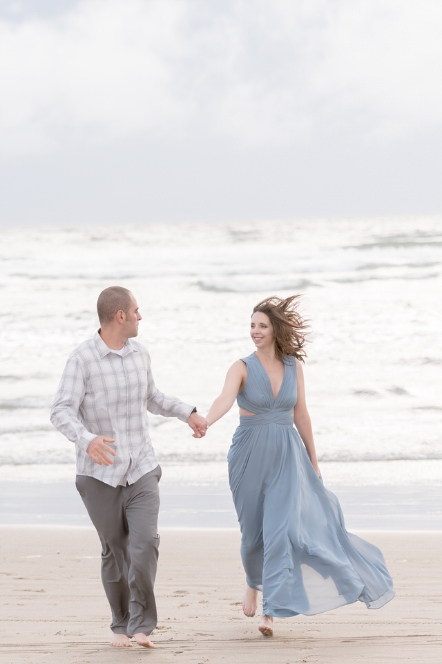 Couple running on the beach in gown romantic engagement