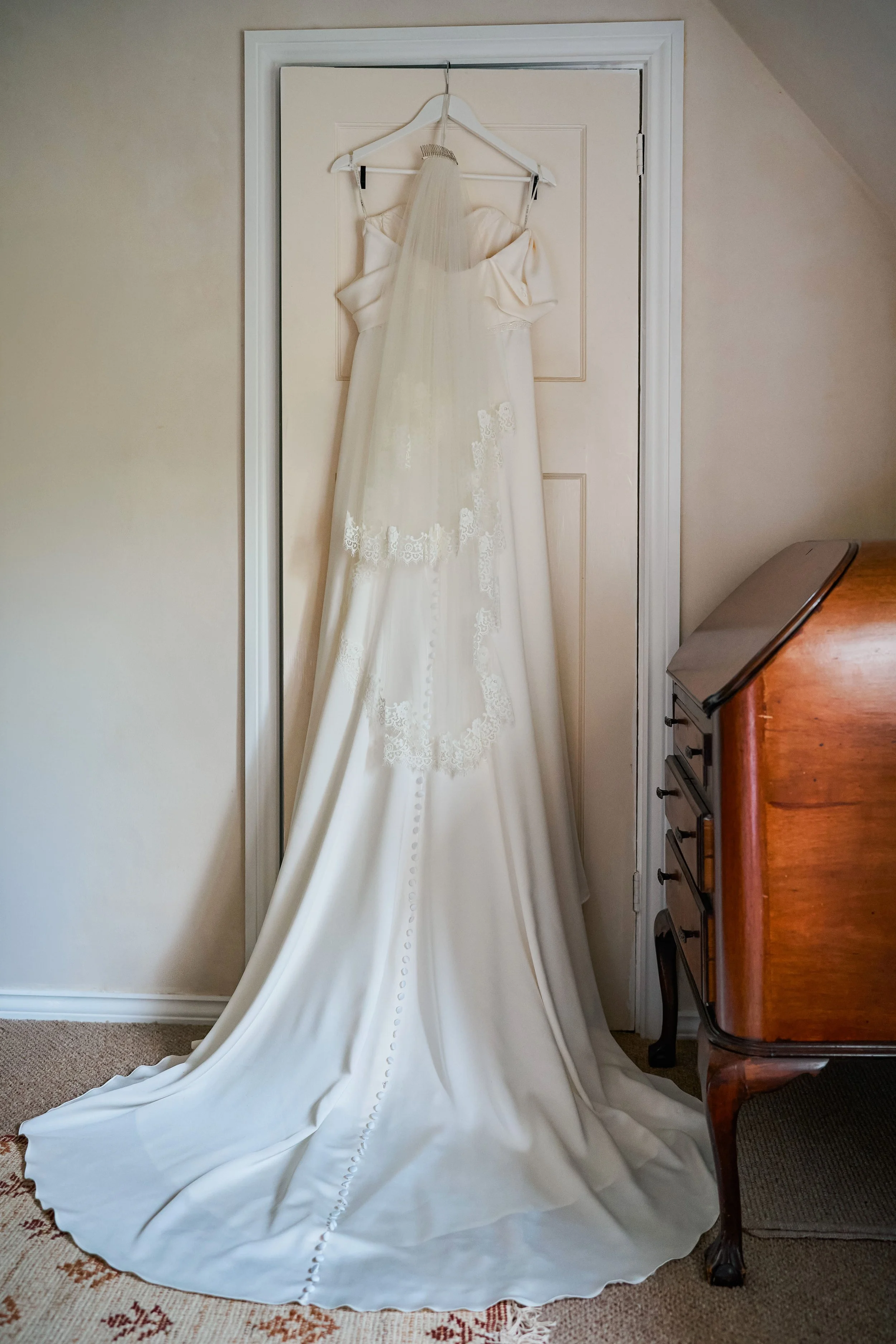 A beautiful wedding dress and veil hanging on door ready for an informal oxfordshire wedding