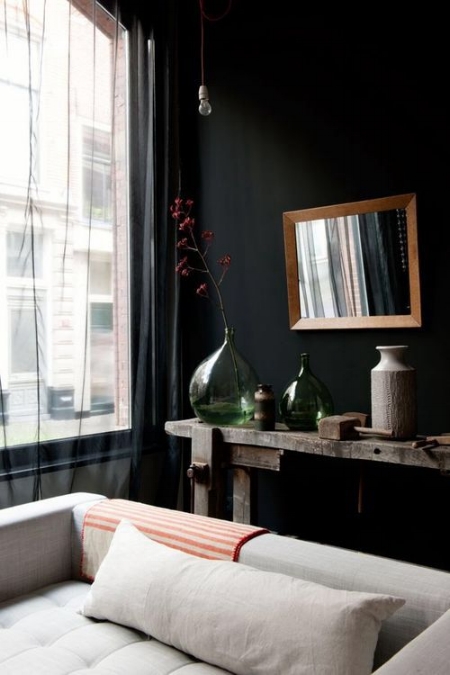 Black walls and black sheer drapes cast a backdrop to all things neutral in this cozy living area. Image via Mad about the House