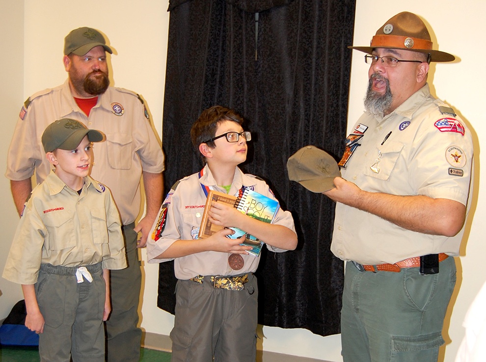  Jack Velez receives Boy Scout Handbook and Scout Cap from Troop Scoutmaster Chris Velez while Assistant Scoutmaster Justin Bristol and Boy Scout Kyle Bristol look on. (photo provided) 