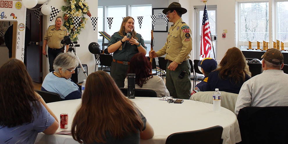   Haley Sylvan, Senior District Executive at Longhouse Council, BSA, presenting a walking stick to Gouverneur Cub Scout Pack 2035 Cubmaster Chris Gates to aid him in leading the pack for the foreseeable future. The presentation was made at the pack’s