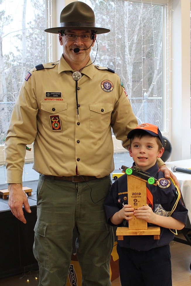   Mason Hilton won the Second Place trophy for his tanker derby car with a camouflage paint job and green wheels. Mason Hilton is pictured (at right) with Cubmaster Chris Gates (at left). (Rachel Hunter photo)  