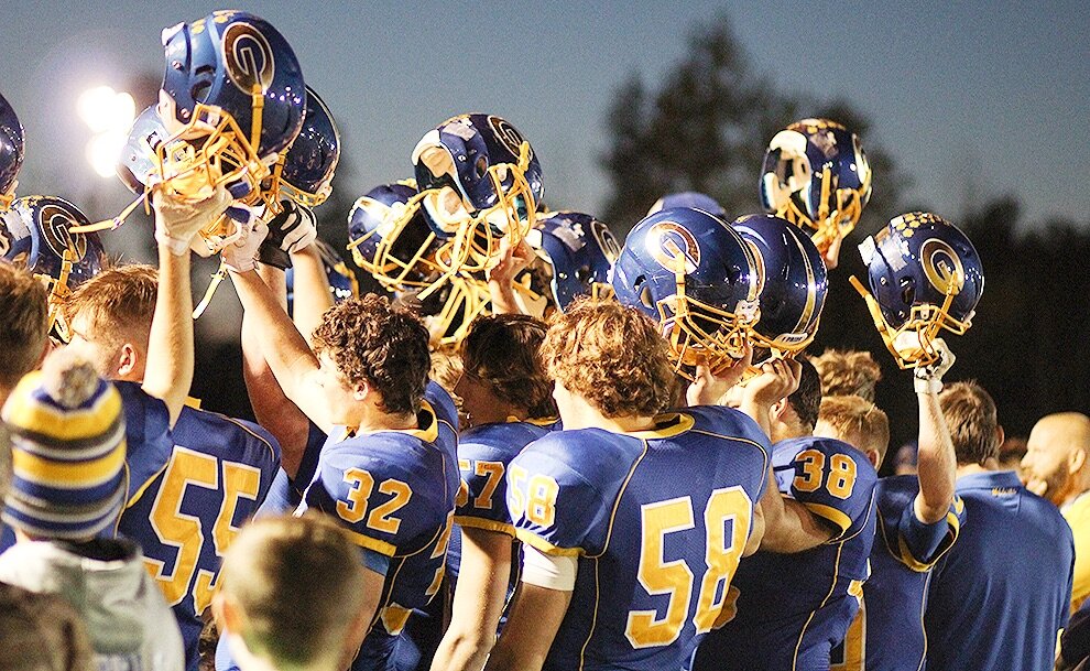   Gouverneur Wildcats lift their helmets in unison as they sing the GHS Alma Mater Song under the lights on the Frank LaFalce Field. (Rachel Hunter photo)  