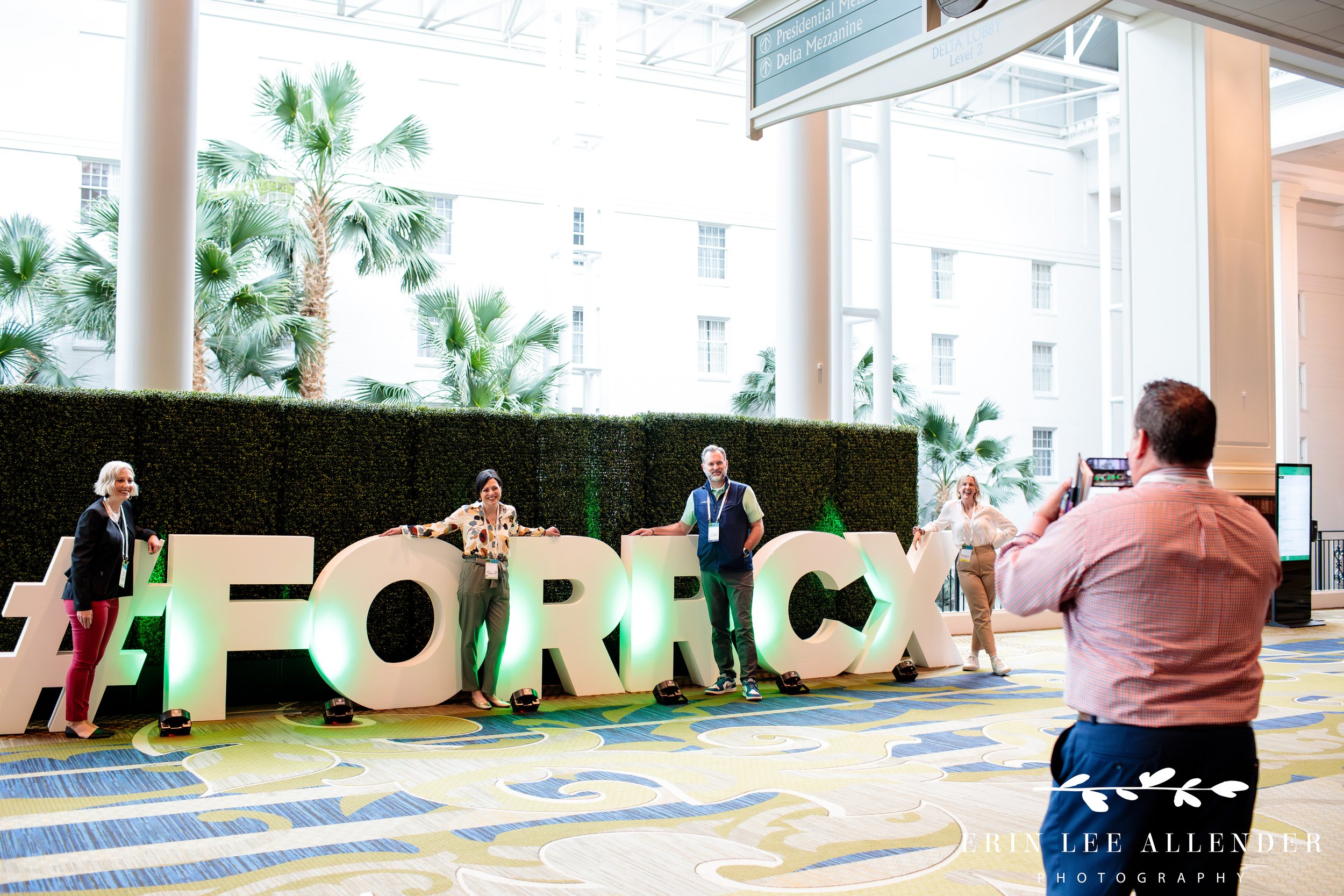 Attendees posing with large CX sign letters at corporate CX conference Gaylord Opryland Hotel