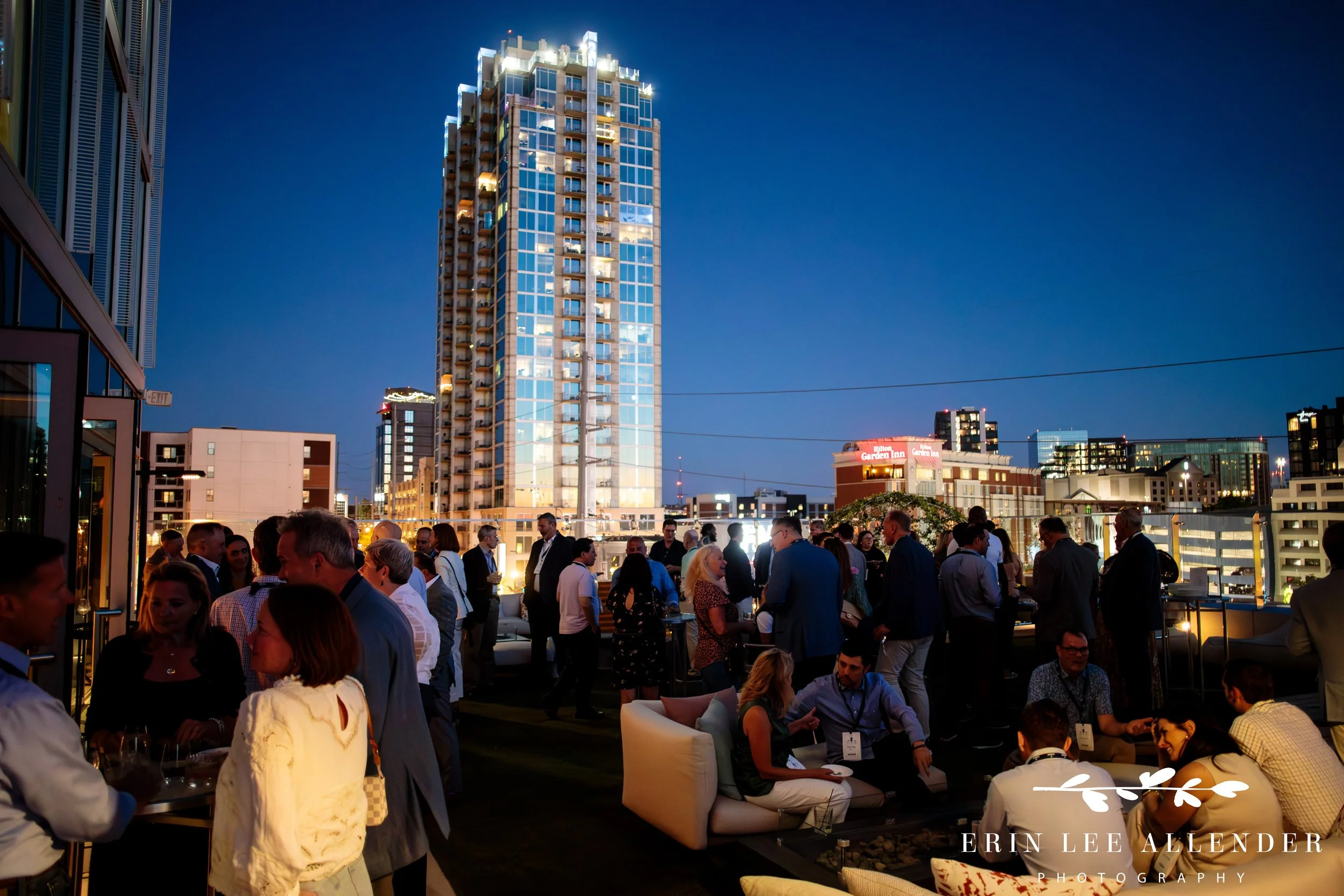 Nashville corporate event photographer — The Conrad rooftop deck at night during CBIZ Nashville Summit welcome reception with downtown skyline