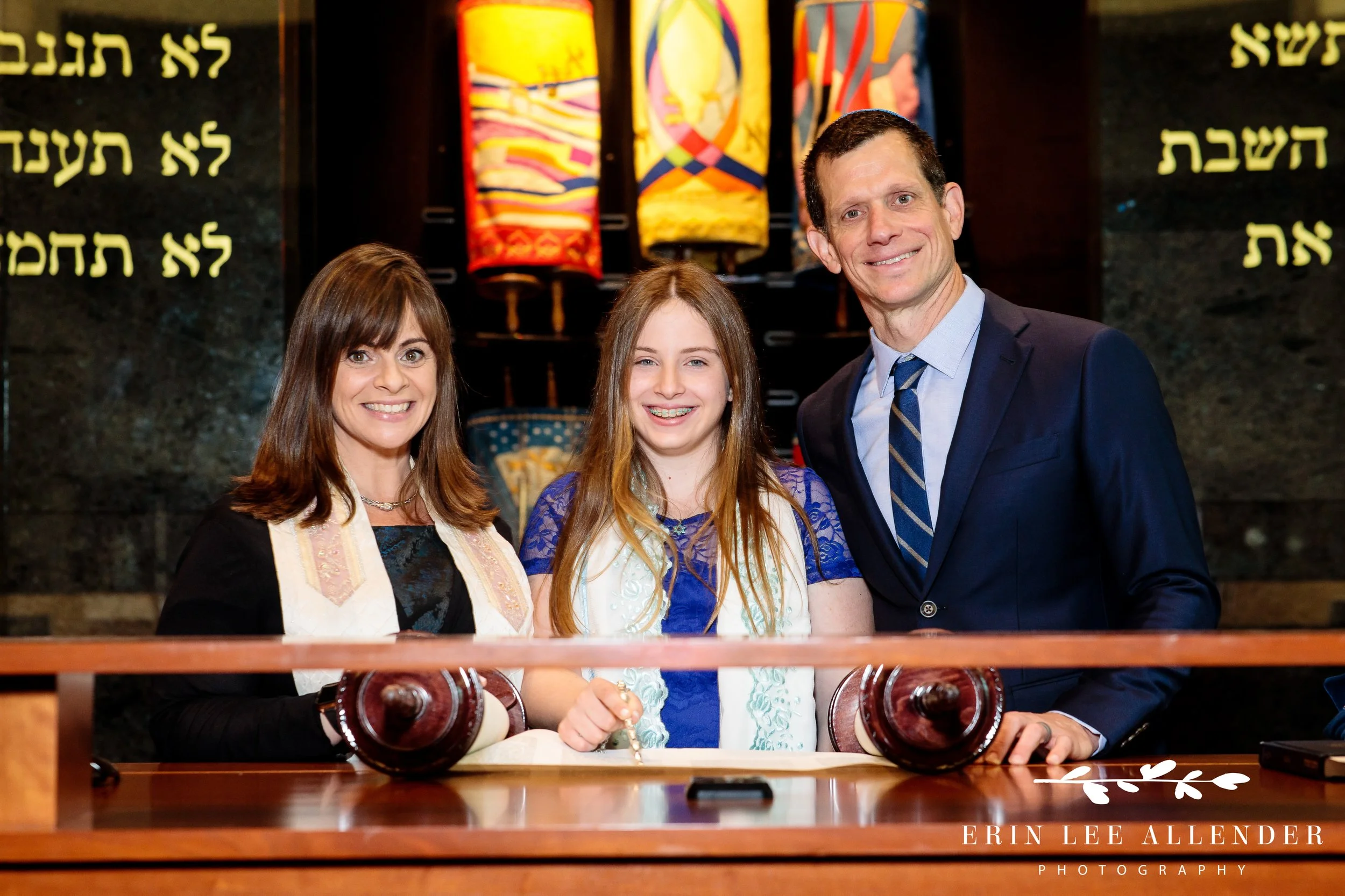 Parents standing proudly with Hannah on the bimah during her Bat Mitzvah service.