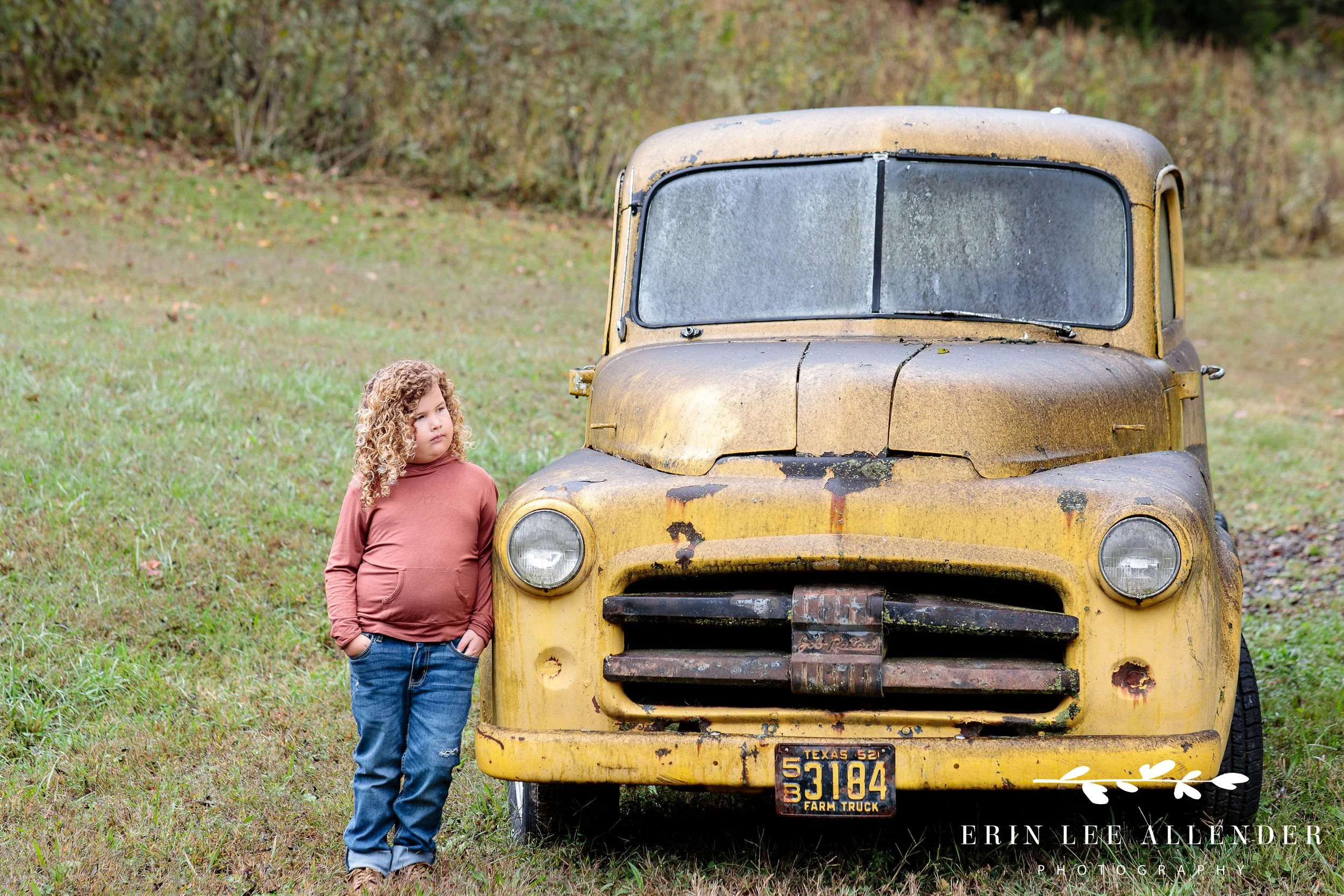 Curly haired boy in front of rustic vintage truck during fall family photos Nashville TN.