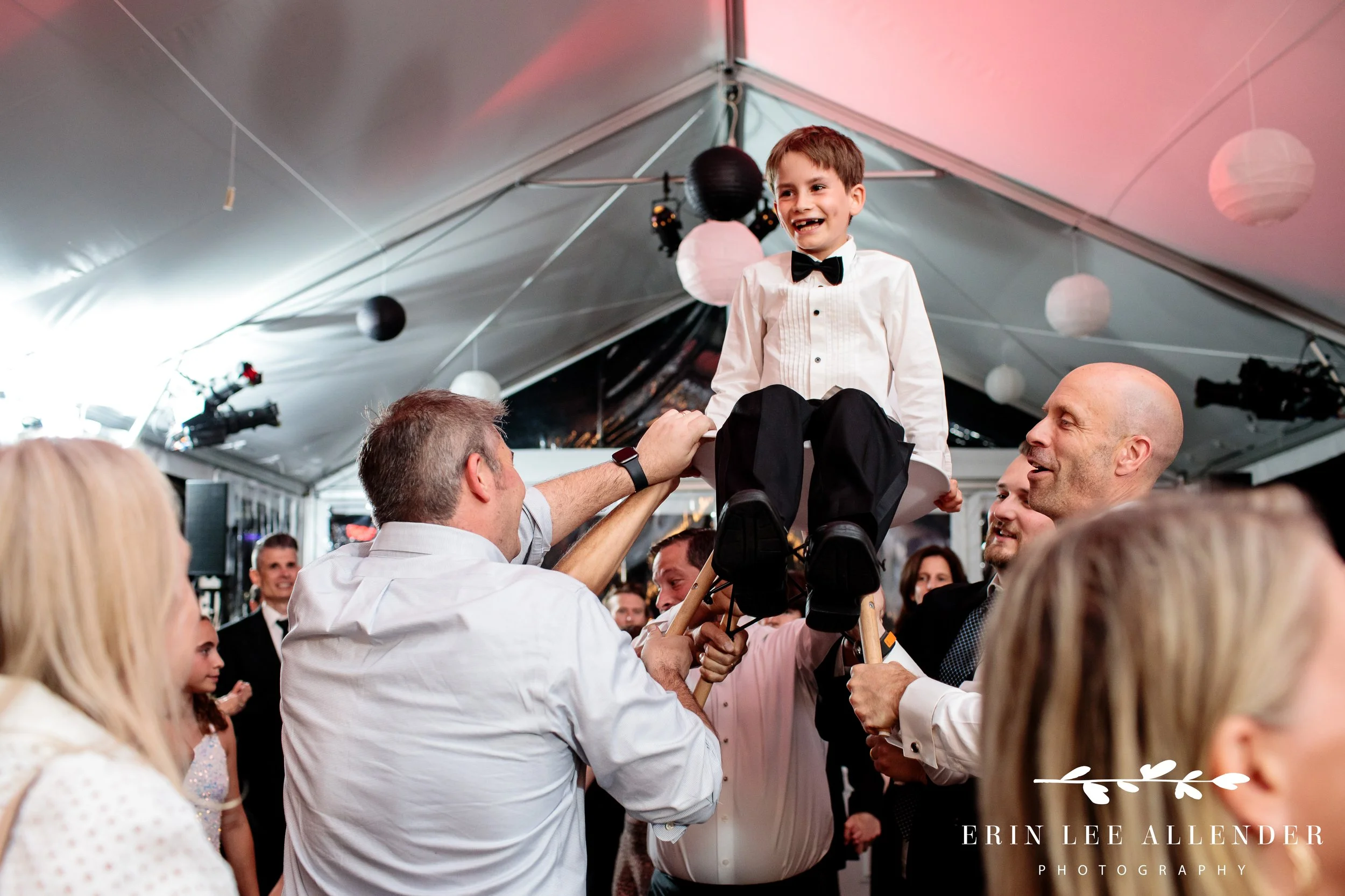 Younger brother lifted in chair during horah at Nashville Bar Mitzvah rooftop party.
